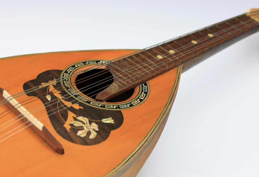 Close-up of an acoustic mandolin with decorative rosette and inlay in a light wood finish.