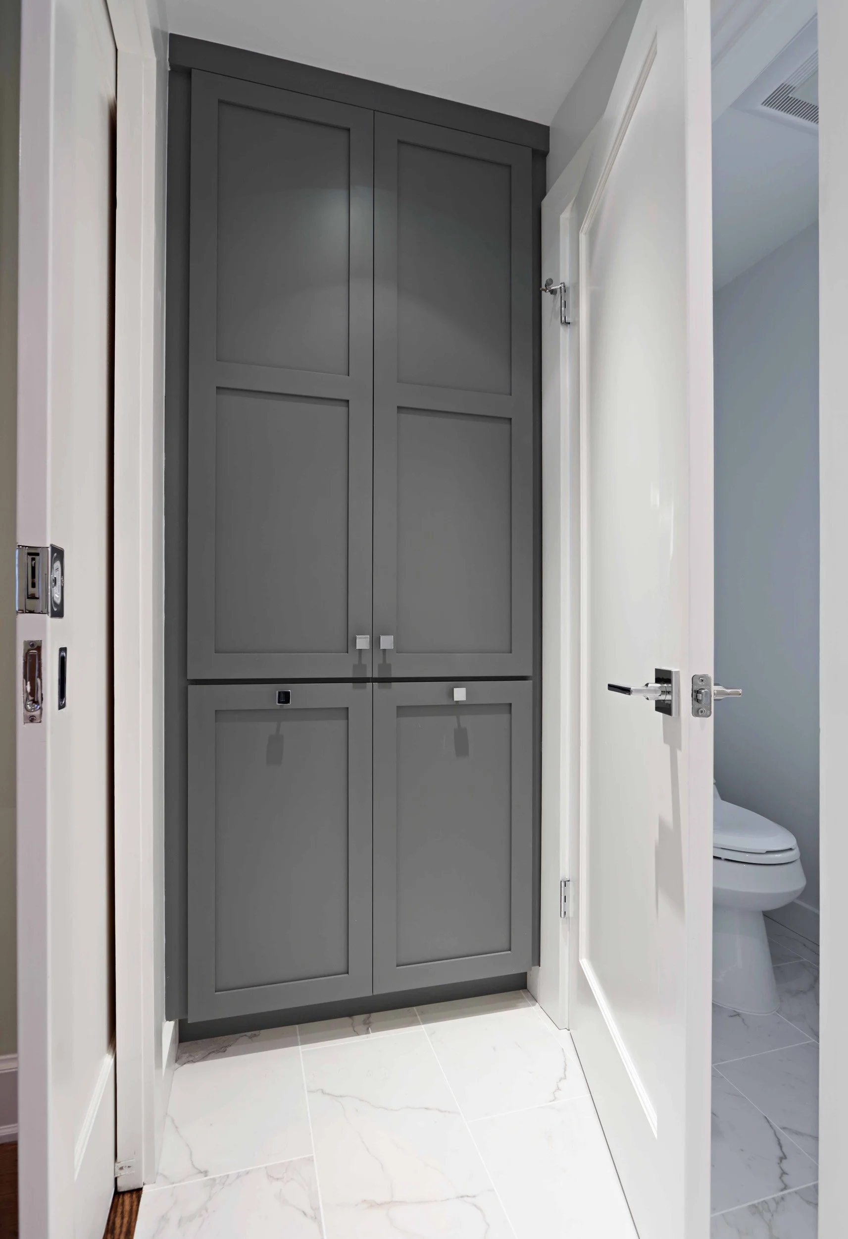 Close-up of a custom built-in linen closet with tilt-out hamper, painted cabinetry, and integrated hardware.