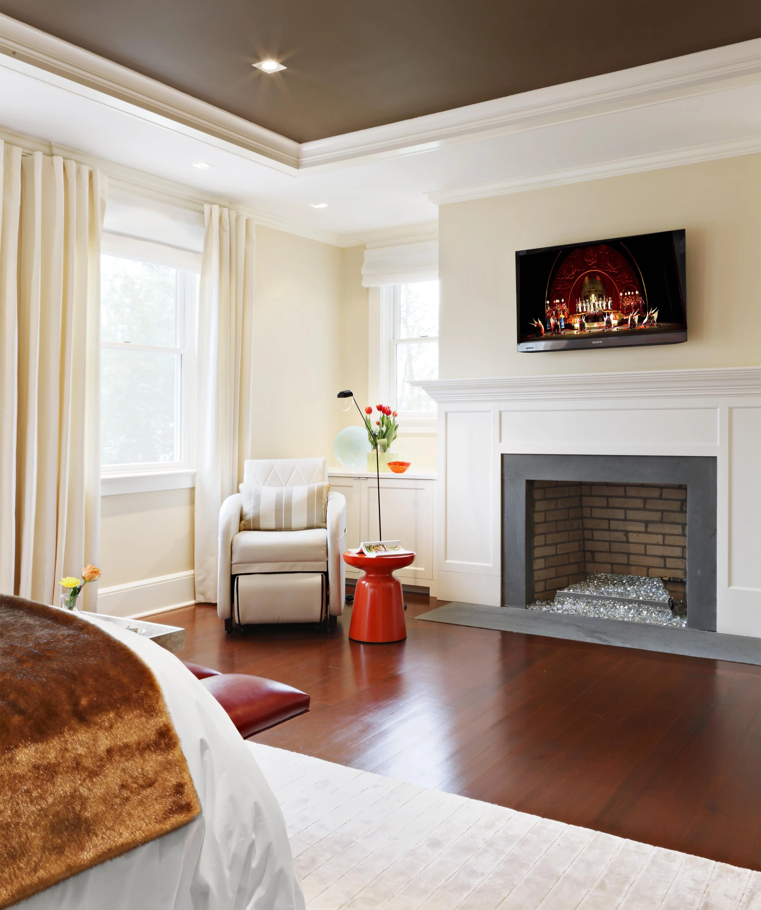 Alternate wide view of primary bedroom highlighting seating area and gas fireplace.