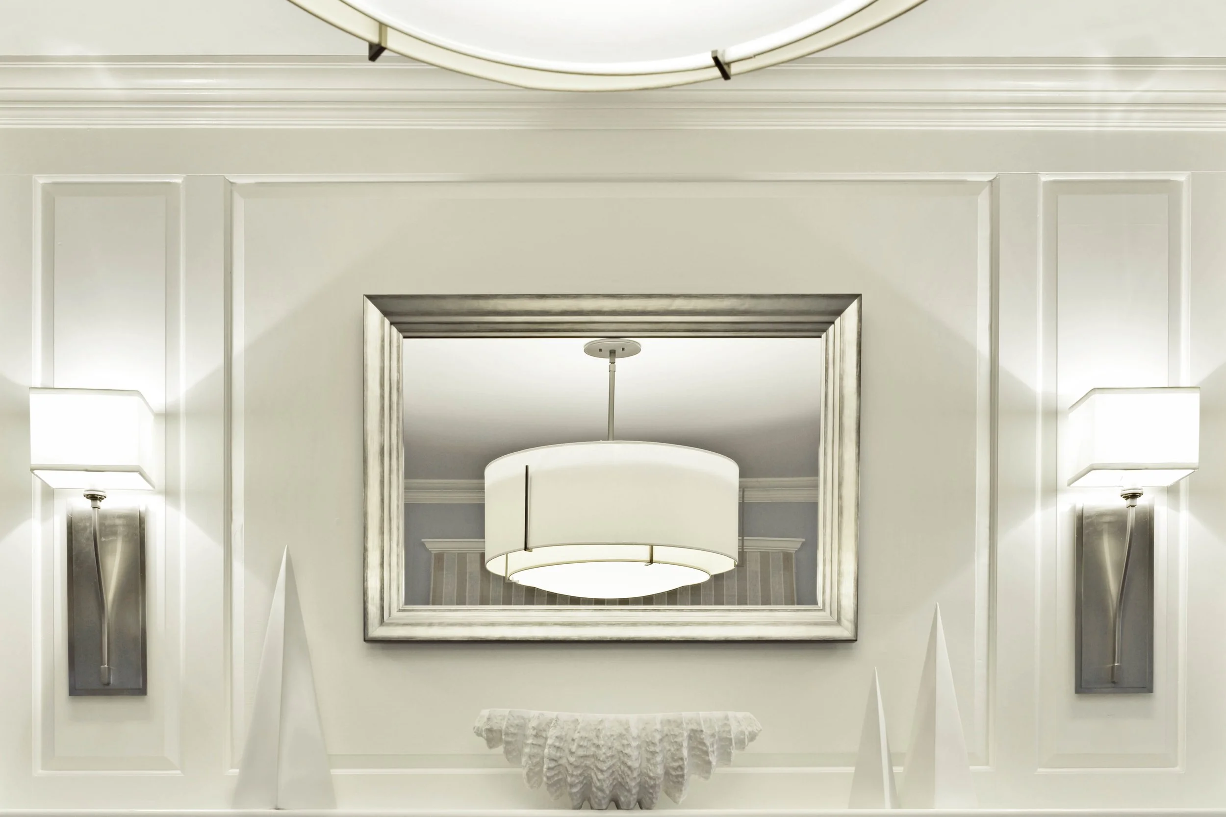 Fireplace mantle detail with refined trim, mirror, and chandelier.