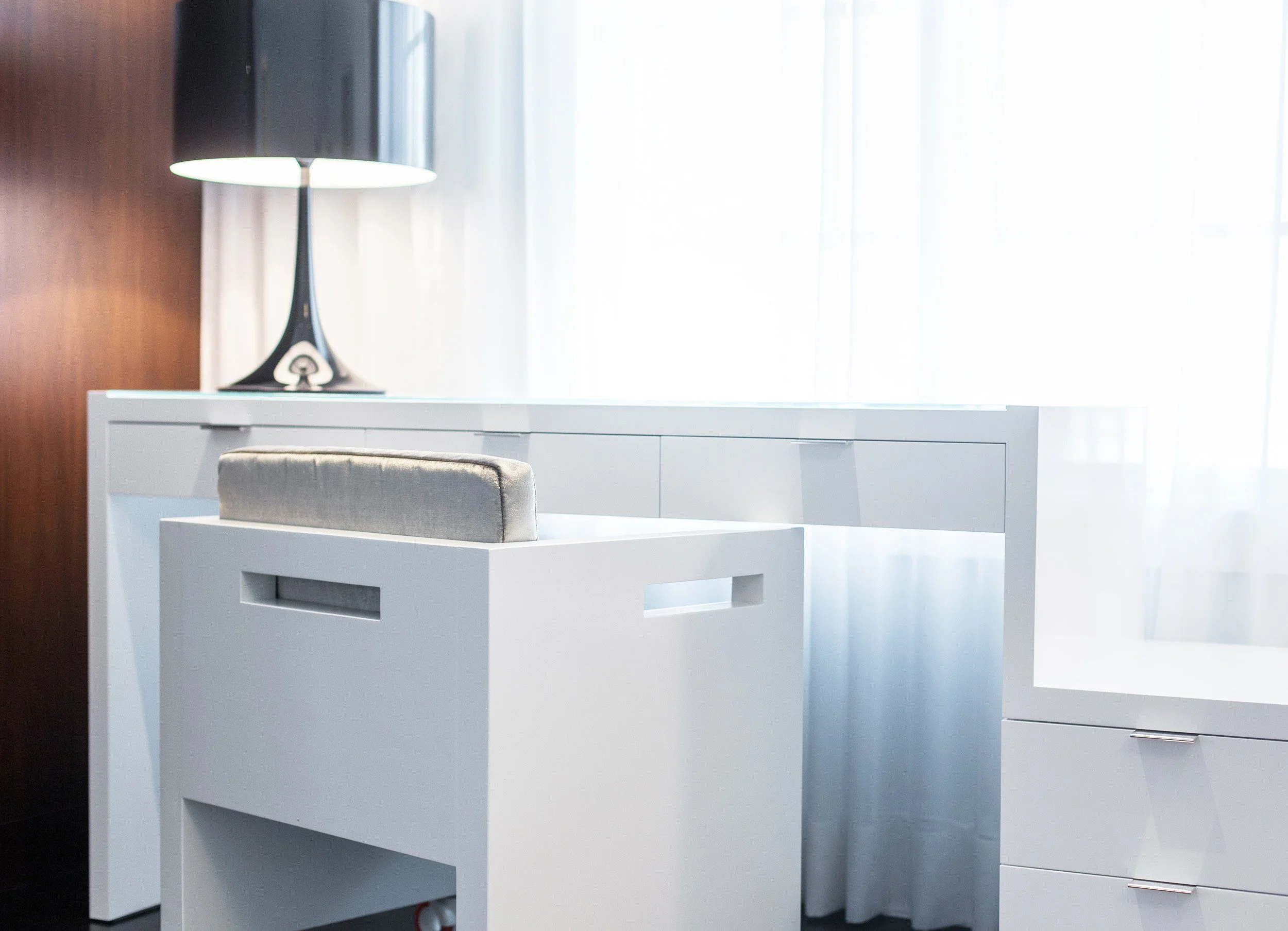 Detail shot of a minimal desk vignette with a custom white desk, upholstered chair, and black table lamp by the window in primary bedroom in Kensett House in Darien, CT. 