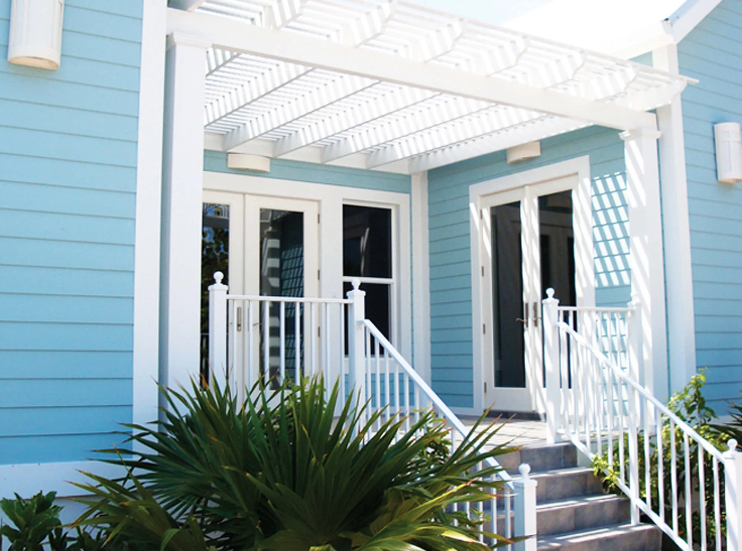 Entry detail of coastal guest villa in Grand Cayman with pergola and light blue exterior.
