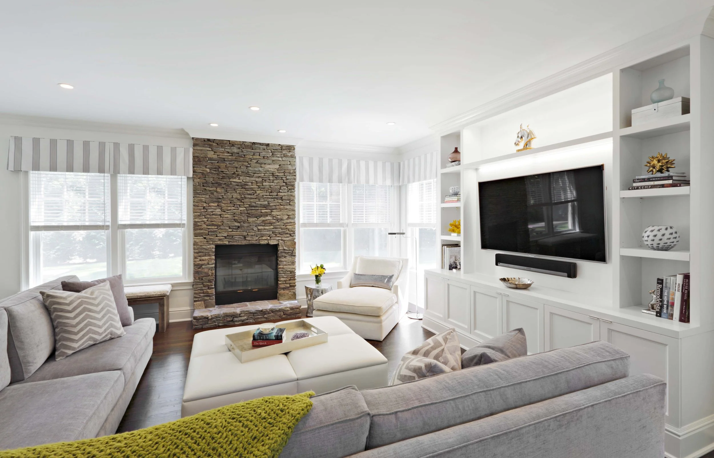 Family room in Parkfield House in Scarsdale NY home with custom media cabinets and stone fireplace designed by Luminosus Designs.
