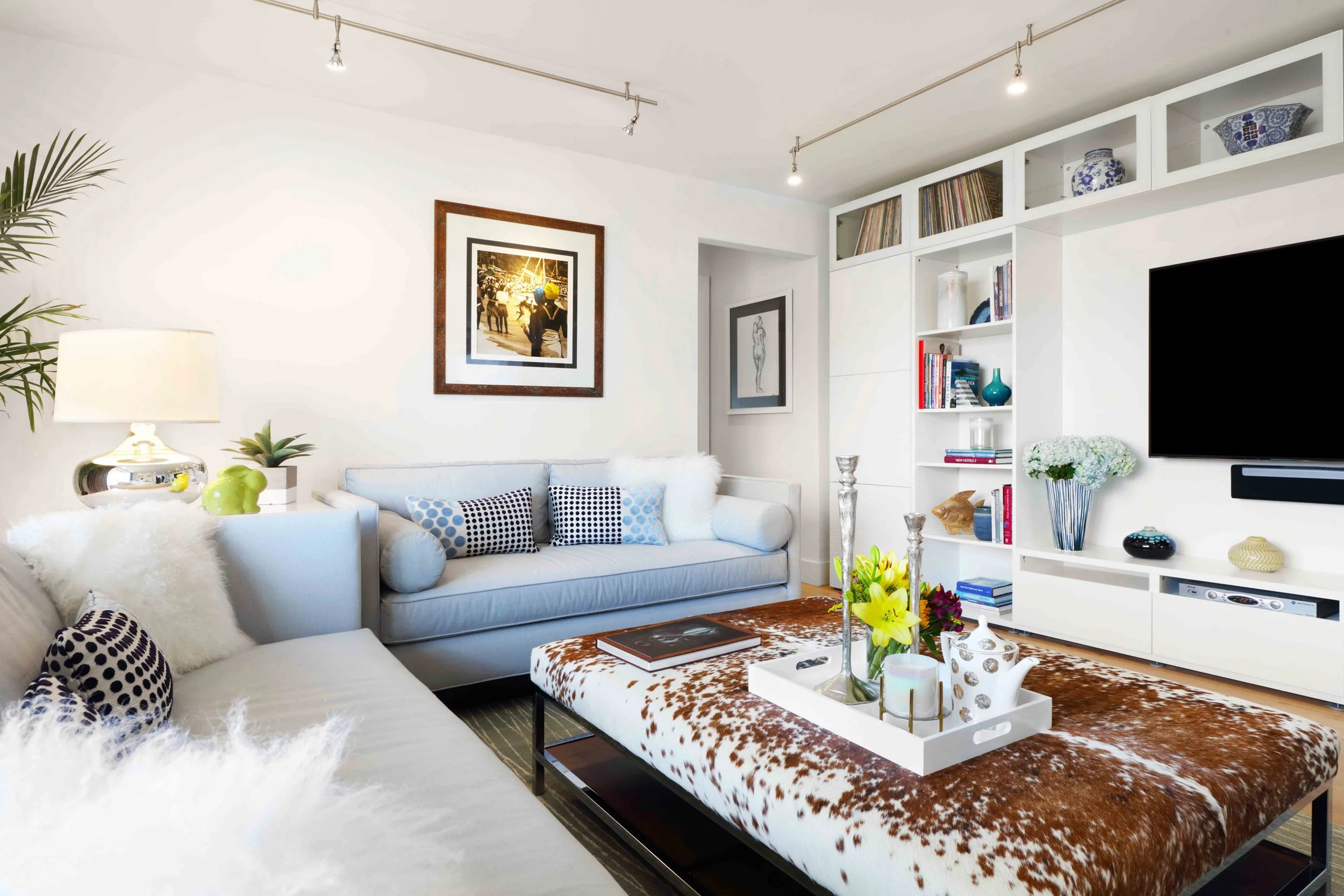 Airy living room seating arrangement with neutral upholstery, soft textures, cowhide coffee table, and contemporary styling in Doyer Apartment in White Plains, NY.