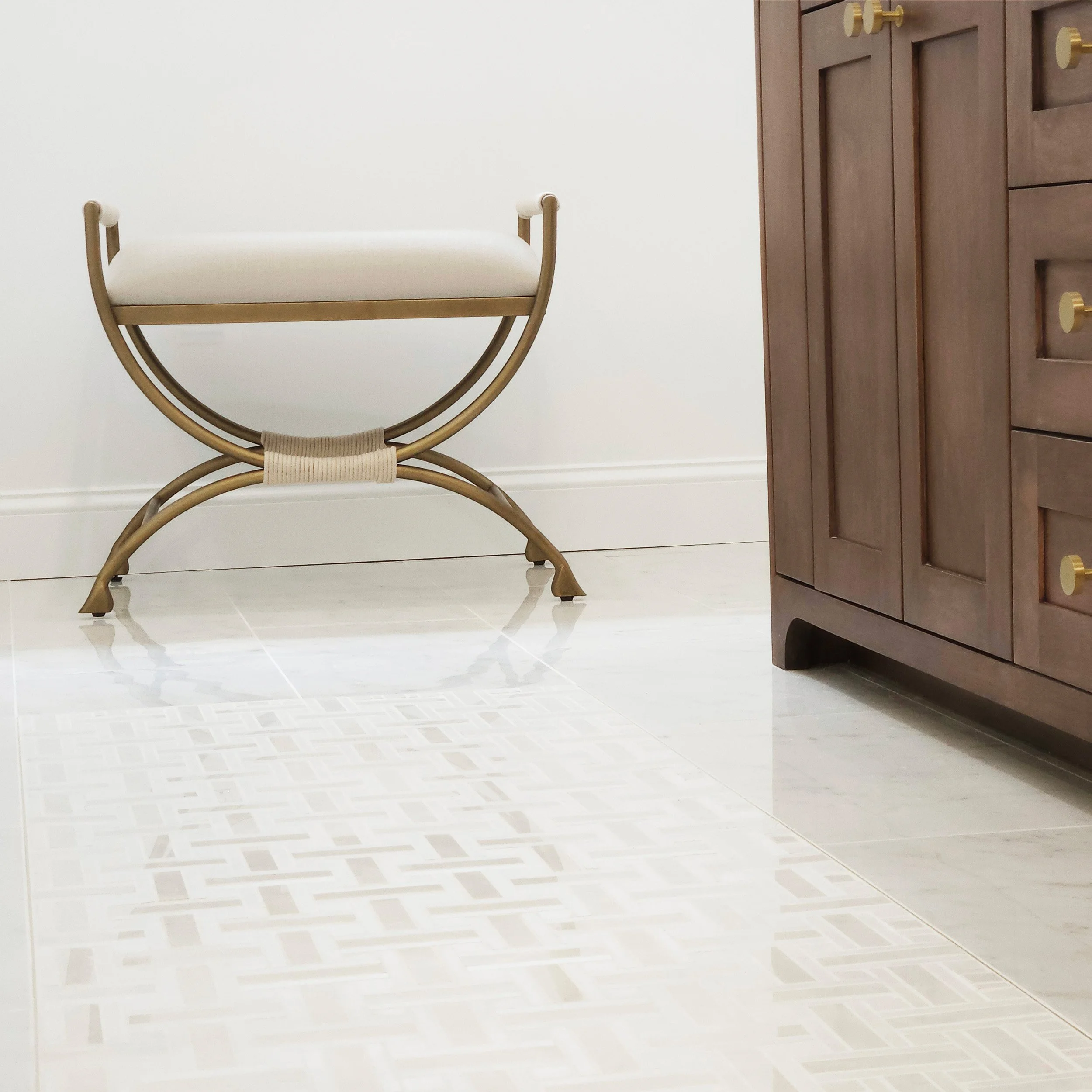 Close-up view of primary bath marble floor detail beside the wood vanity in Carlyle Court in Princeton, NJ.
