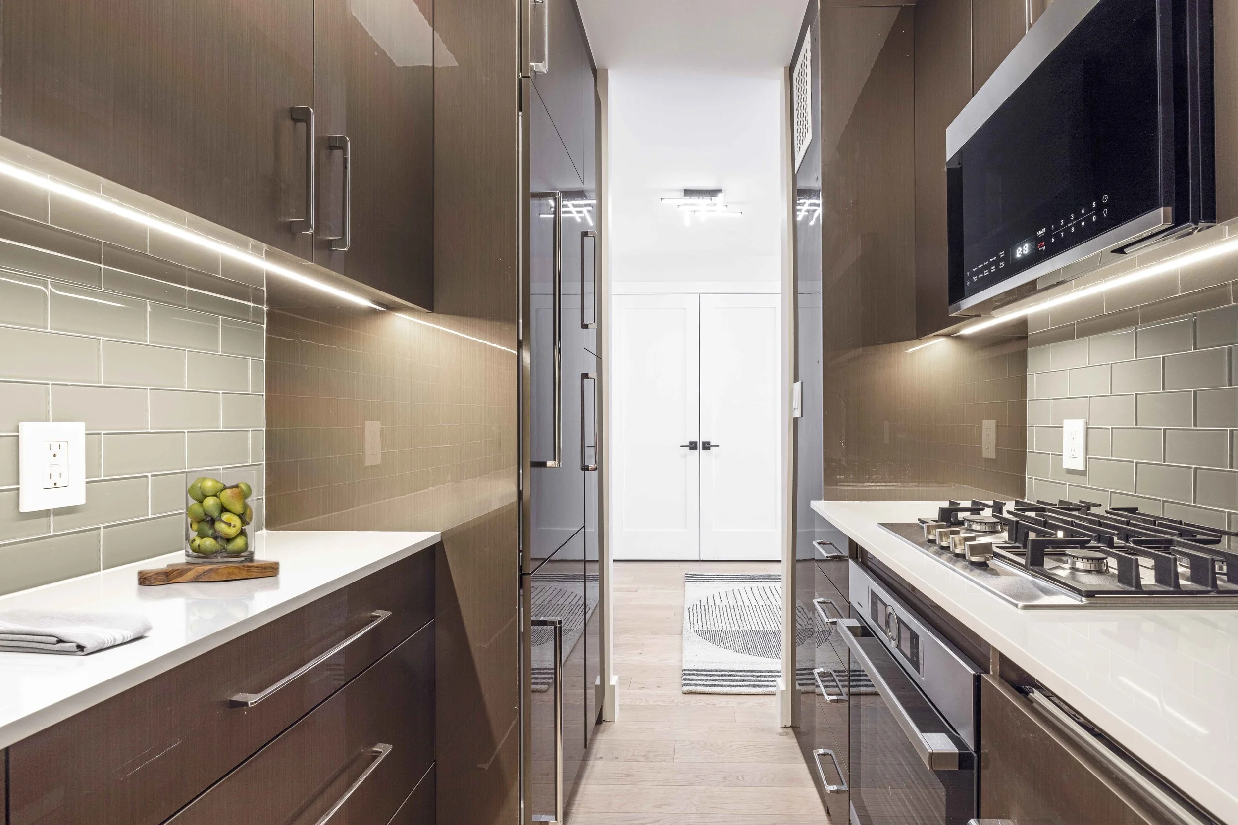 Wide view of the Gramercy Arms kitchen in New York City, showcasing efficient layout, warm cabinetry, and refined detailing by Luminosus Designs.