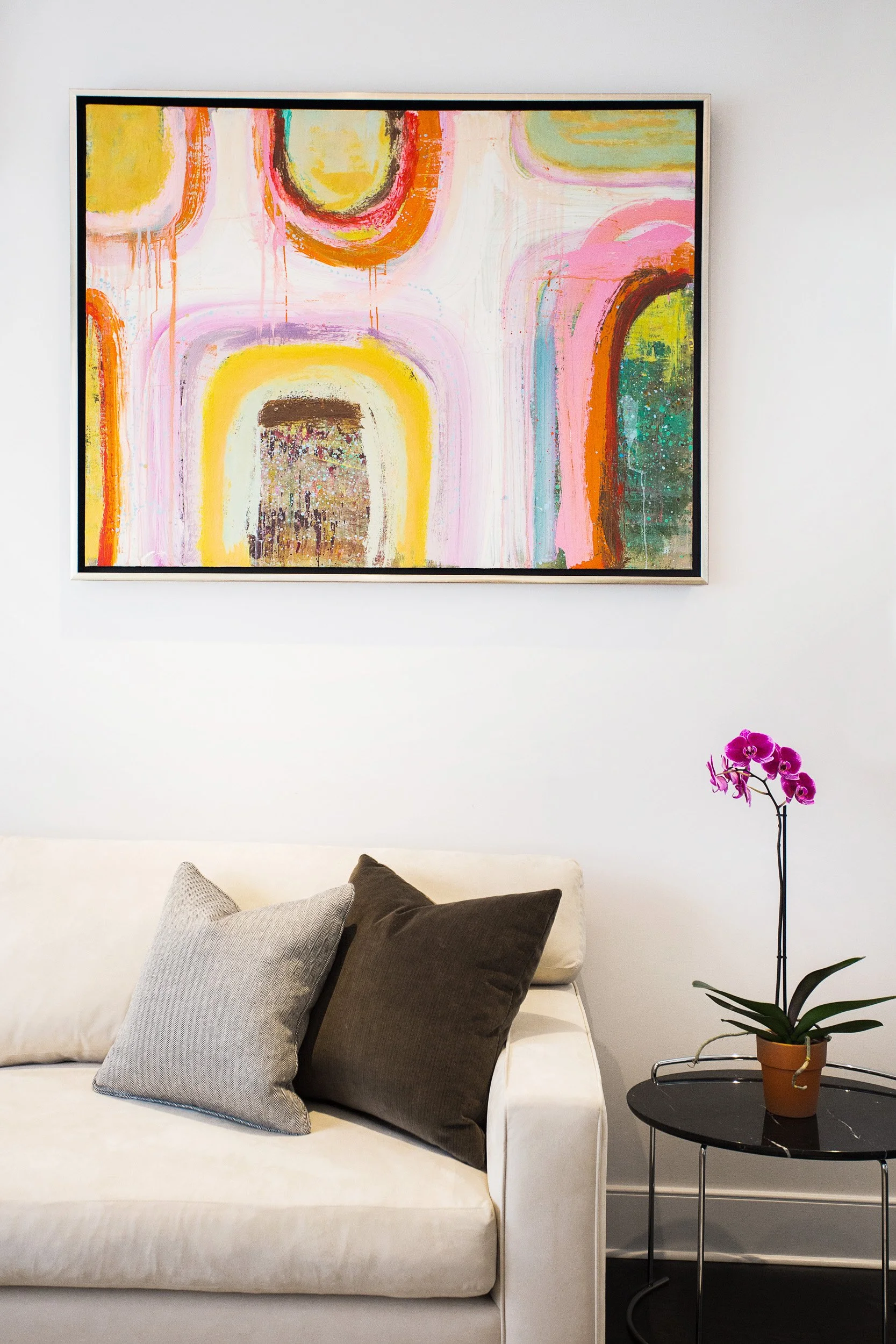 Detail shot of a styled sofa wall with abstract artwork and an orchid arrangement in Kensett residence, Darien CT.