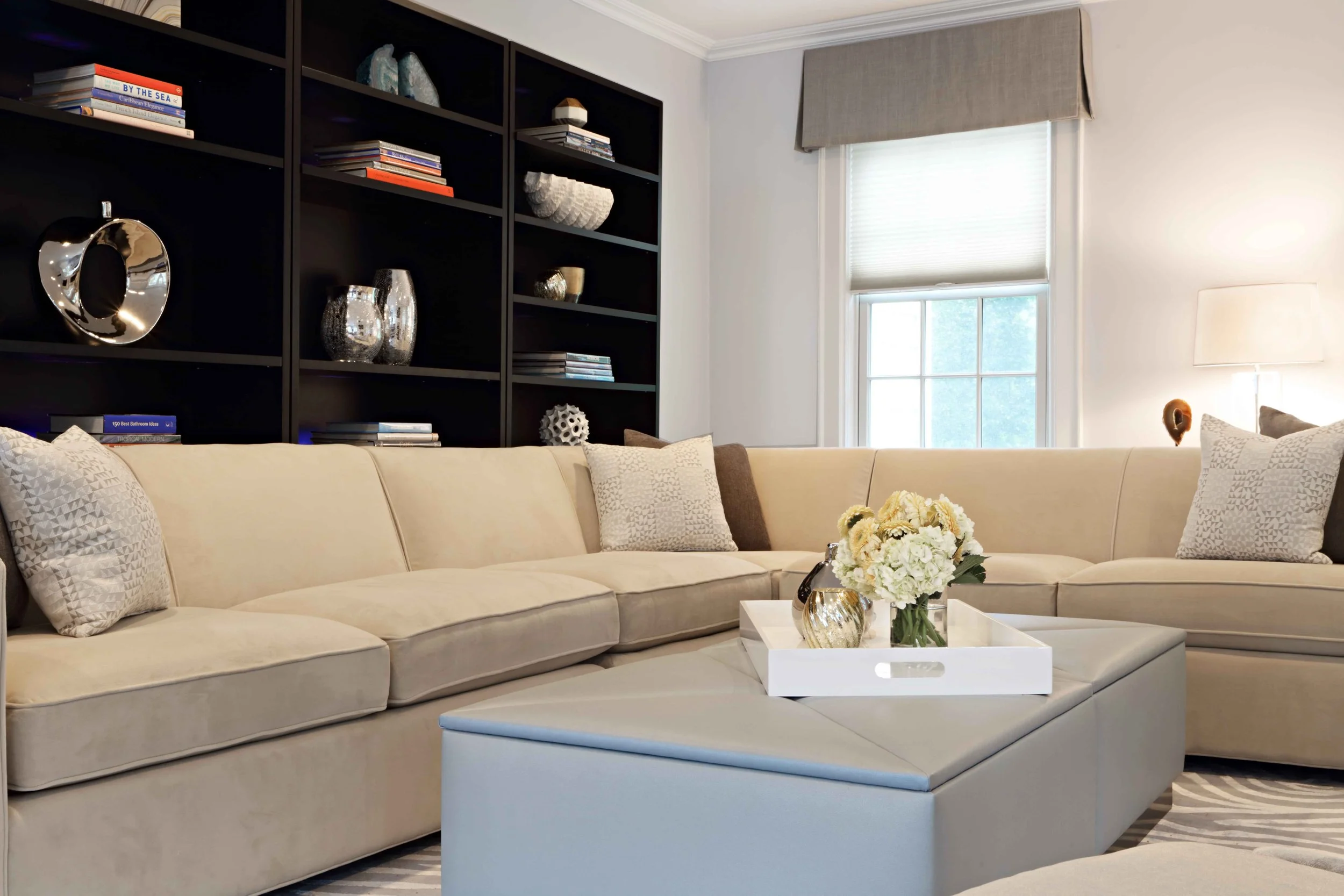 Close-up of a custom upholstered coffee table with integrated storage, styled with decorative accessories in a family room.