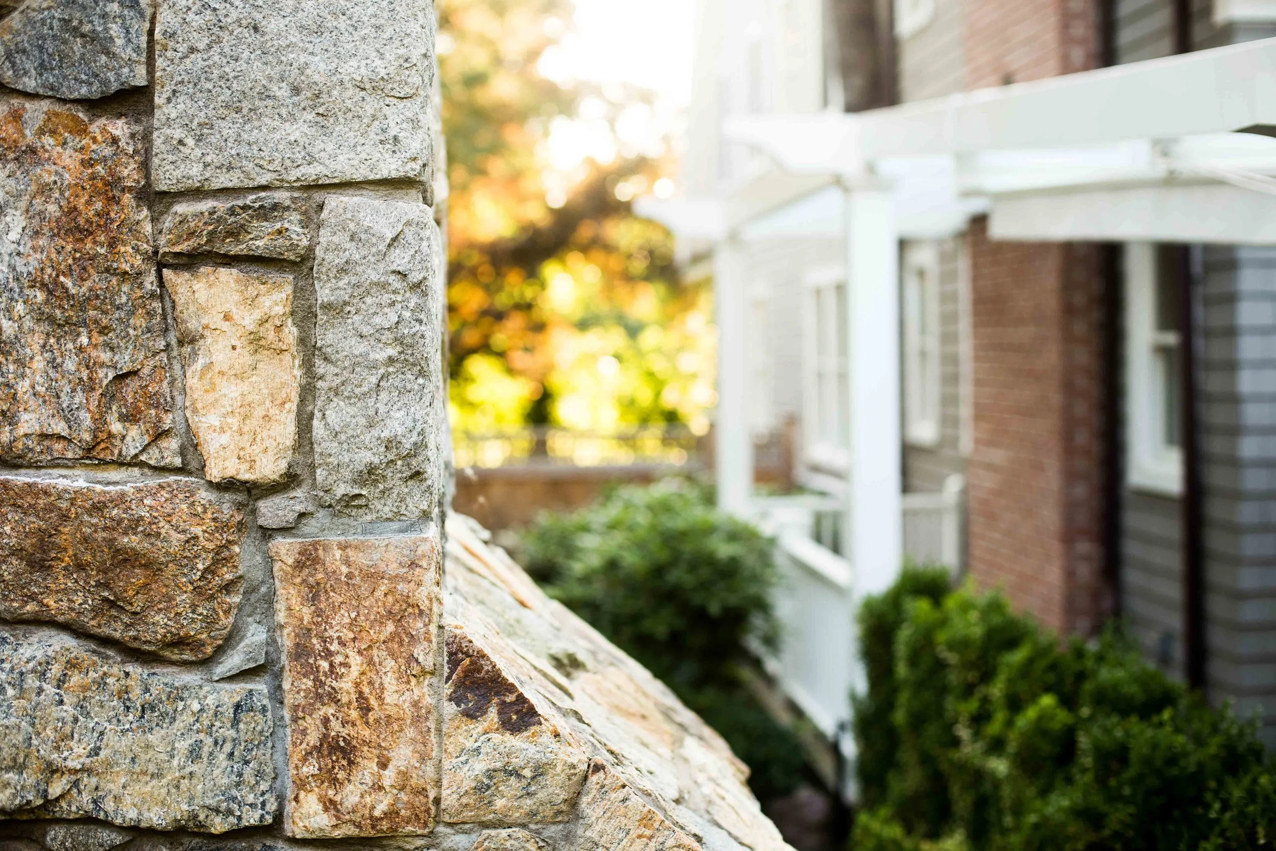 Detail of fireplace stone wall and wrap-around pergola in the outdoor lounge area at the Indian Field Outdoor project in Greenwich, CT.