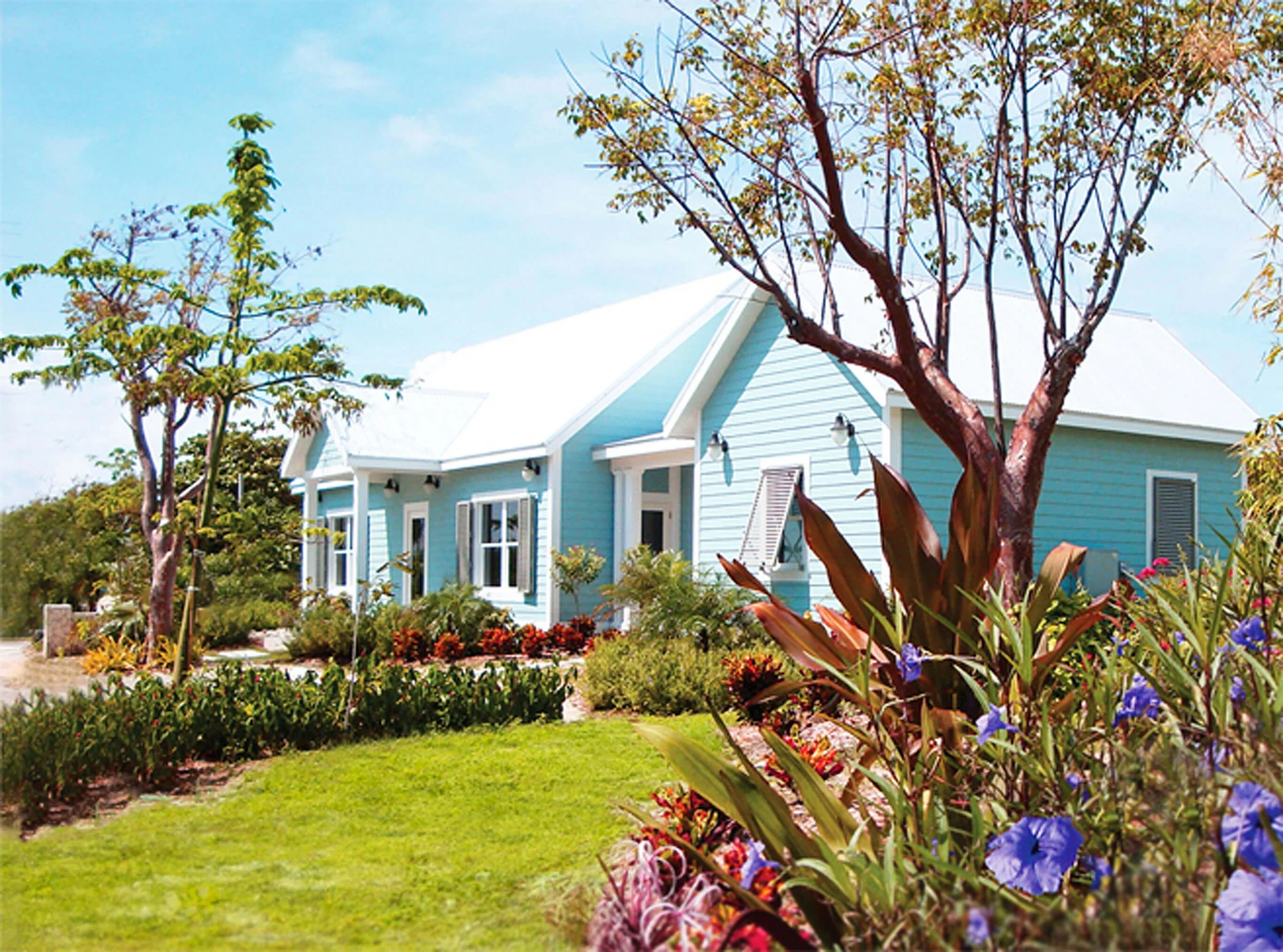 Exterior view of coastal guest villas at Cotton Tree in Grand Cayman with landscaped grounds.