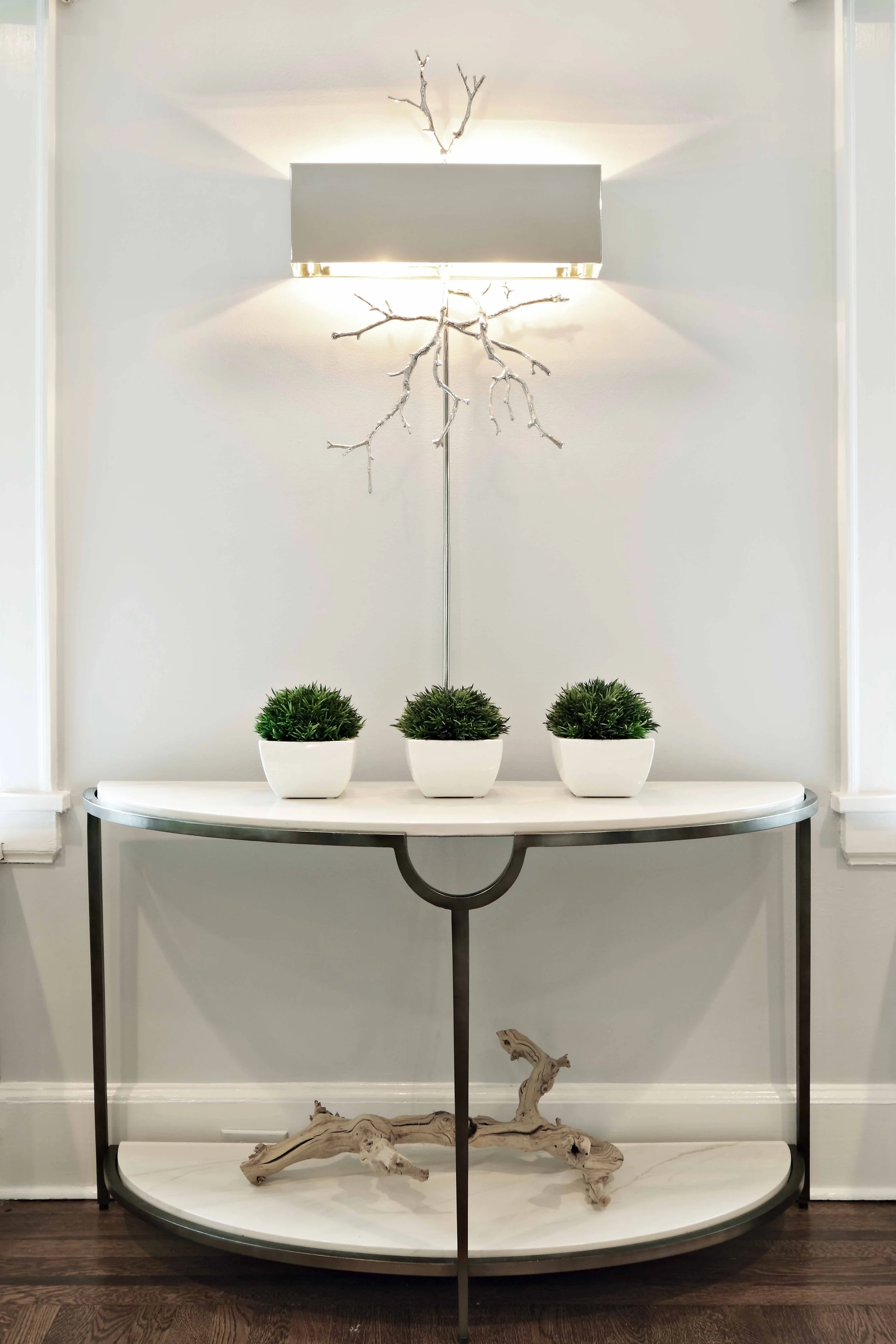 Close-up of a sculptural console table paired with a modern wall sconce, showcasing layered textures and refined styling.