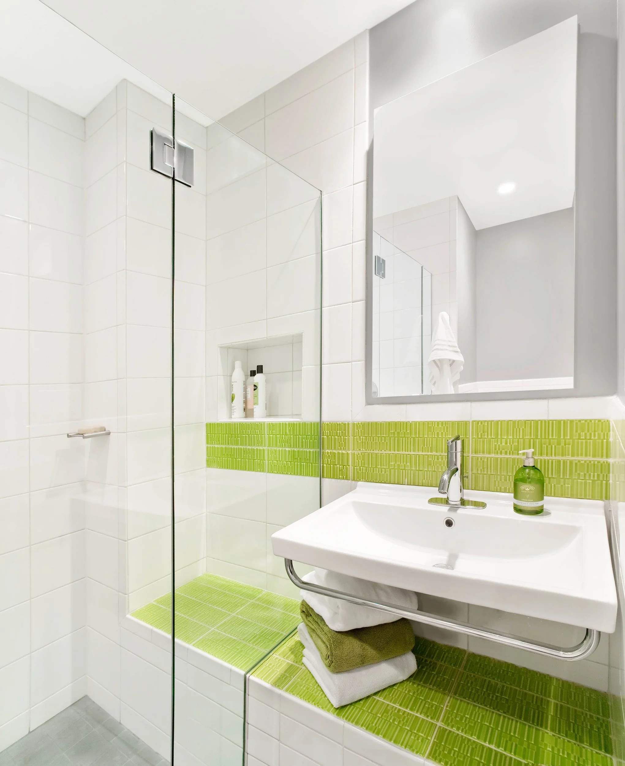 Close-up of a floating vanity with wall-mount sink and custom shower bench in the Deerfield family bathroom in Pleasantville, NY.