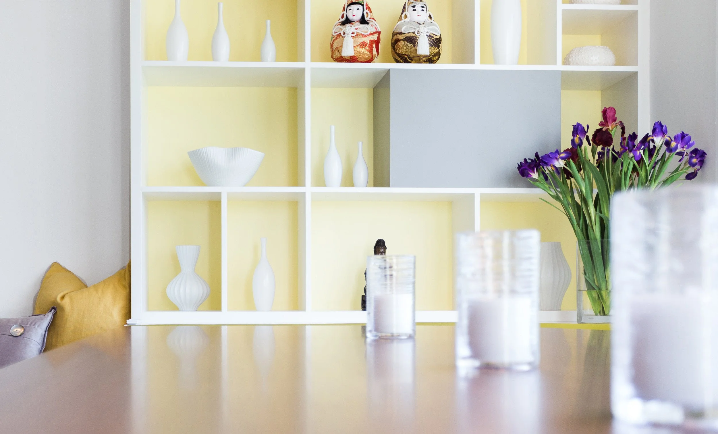Detail shot of built-in shelving with a yellow accent backing and curated decor styling in breakfast area of Kensett House in Darien, CT. 