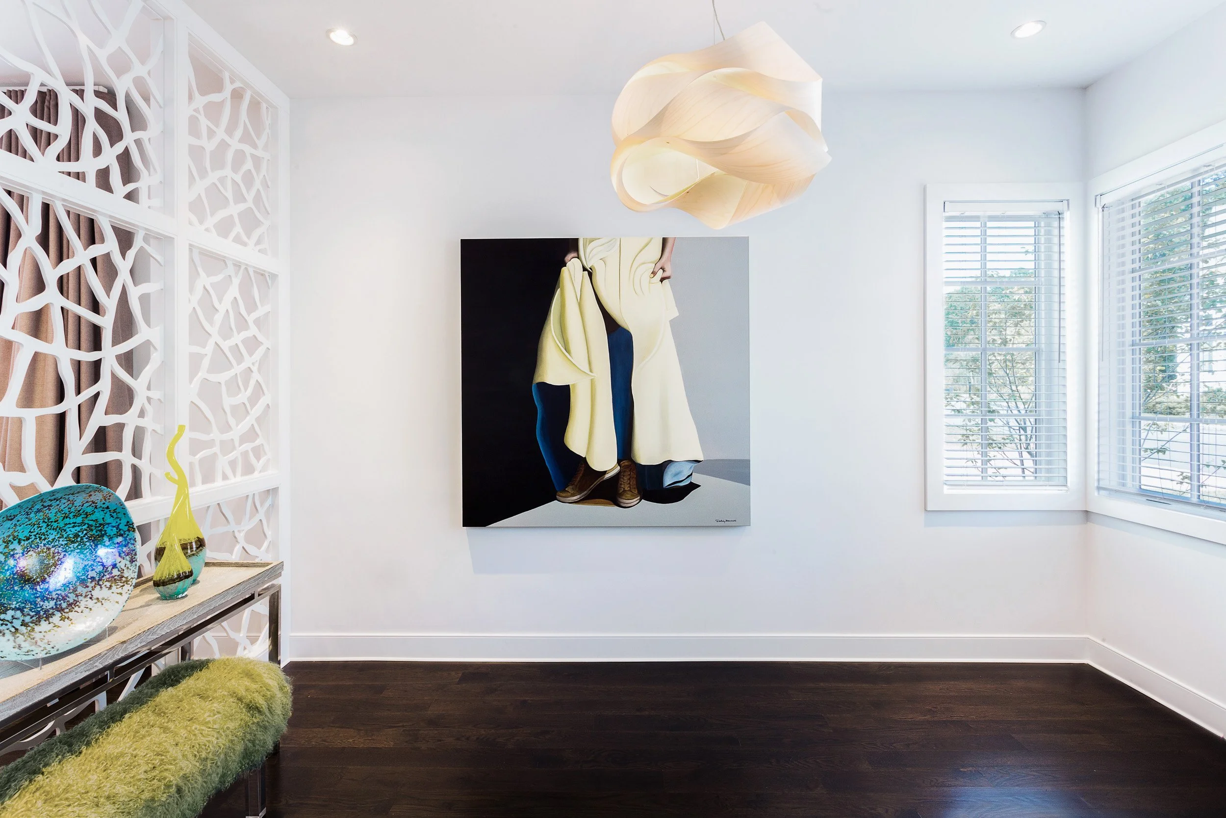 Wide view of a bright foyer featuring a decorative laser-cut screen, sculptural console styling, and modern pendant lighting. Designed by Luminosus Designs.