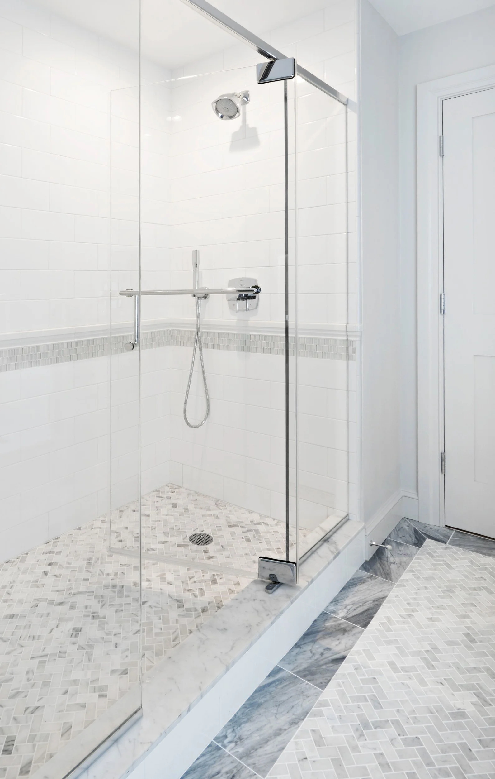 Close-up of a frameless glass shower enclosure with white tile walls in a Jack and Jack bathroom at the Dann Farm home in Pound Ridge, NY.