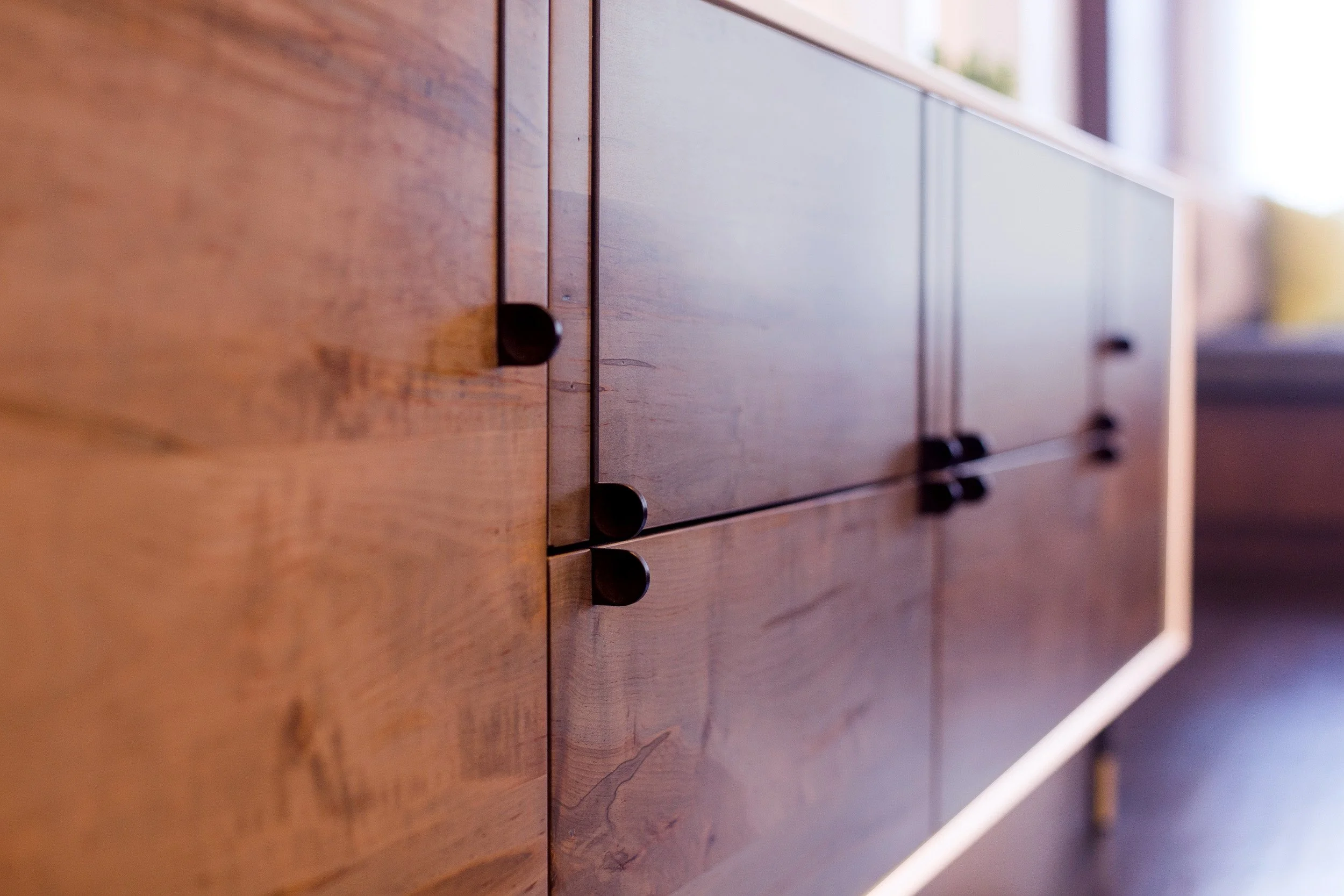 Detail shot of a custom wood dresser with matte black pulls and warm wood grain in Kensett House in Darien, CT. 