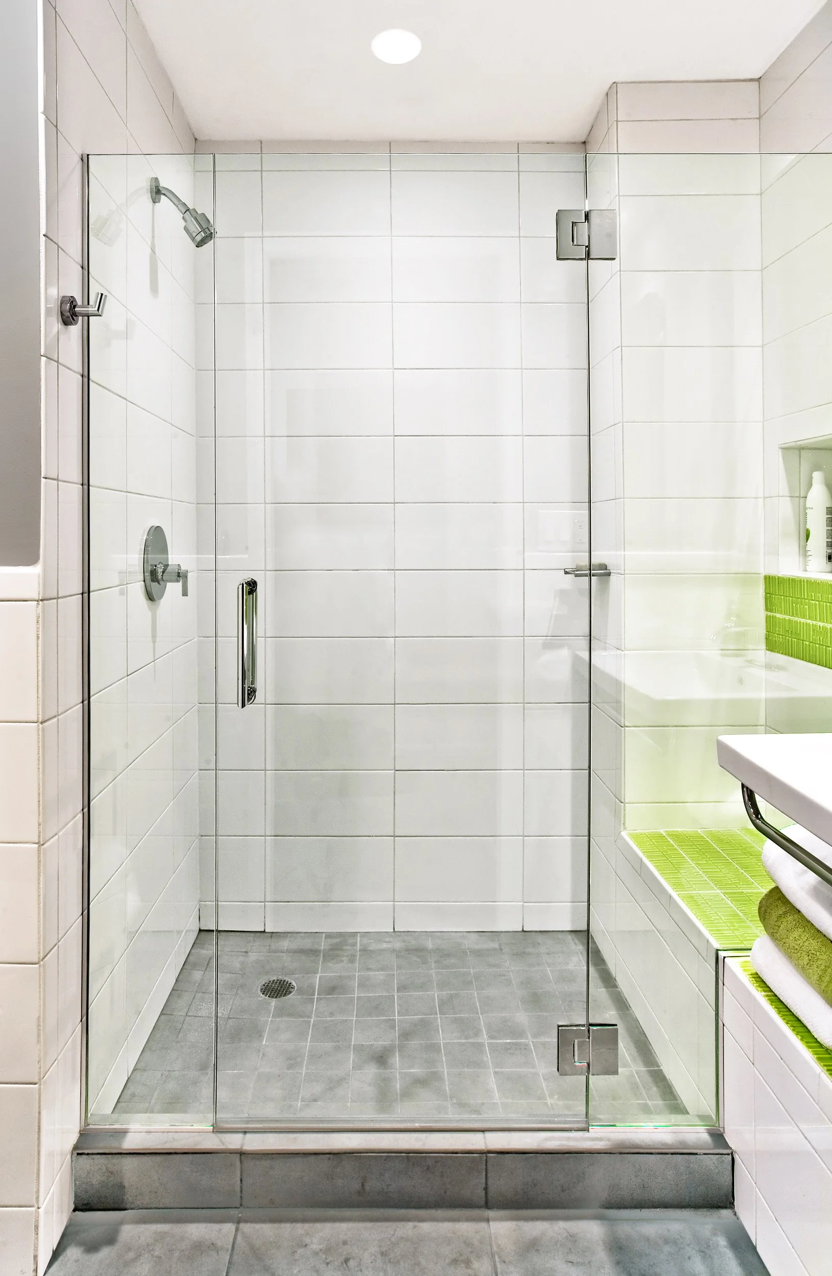 Glass-enclosed shower with vibrant tile detailing in the Deerfield family bathroom in Pleasantville, NY.