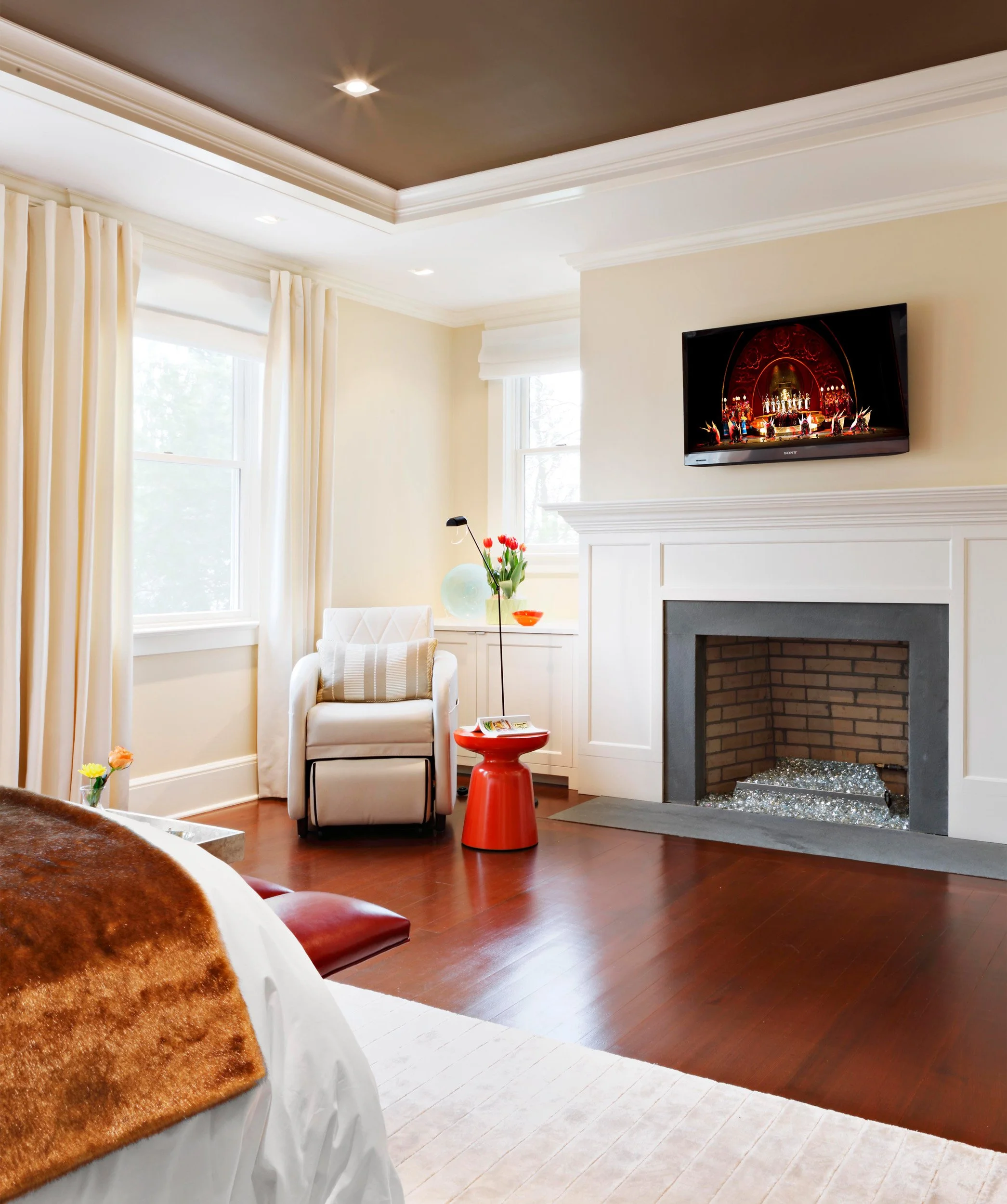 Alternate view of primary bedroom highlighting seating area and gas fireplace in Indian Field residence in Greenwich, CT.