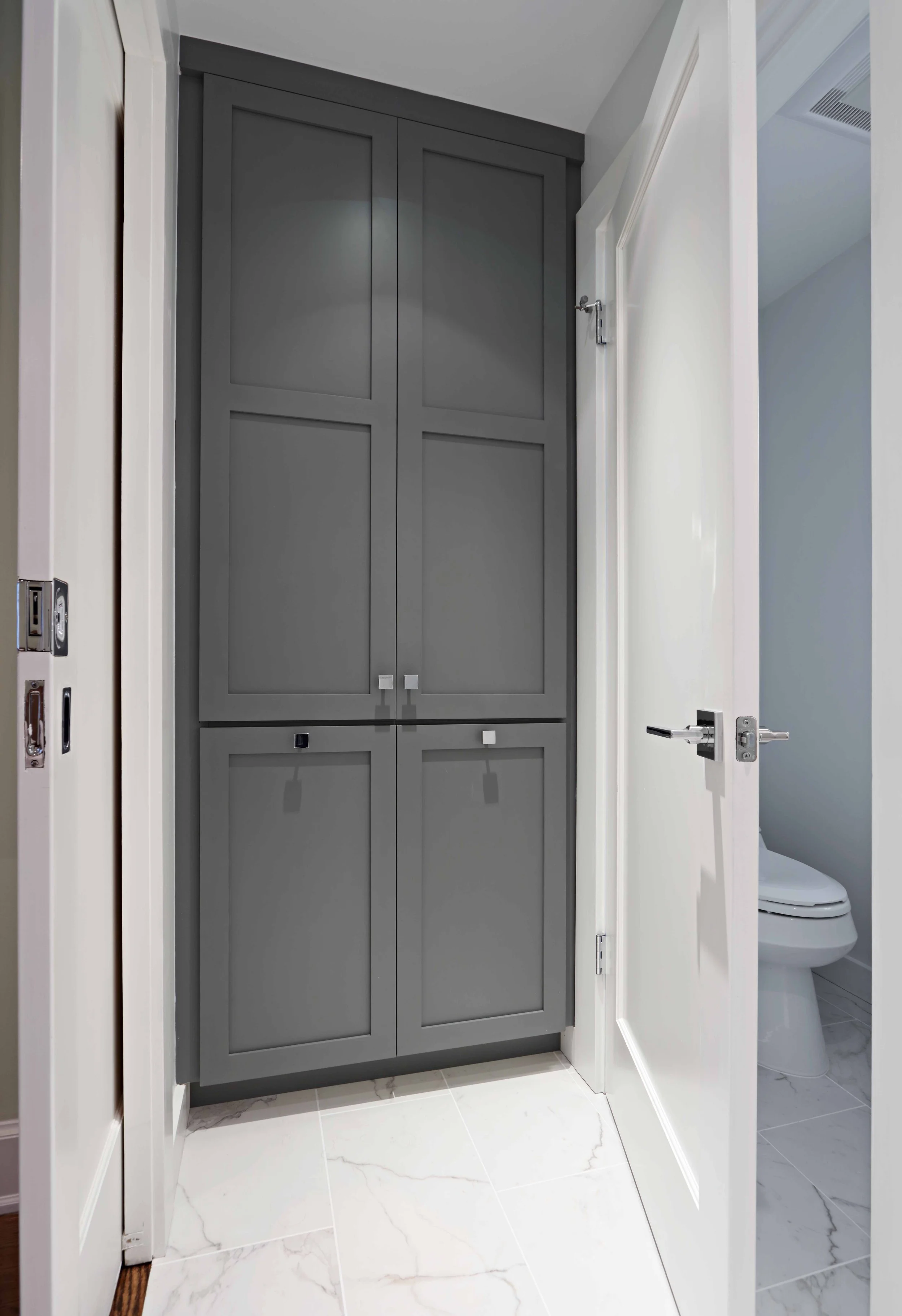 Close-up of a custom built-in linen closet with tilt-out hamper, painted cabinetry, and integrated hardware.