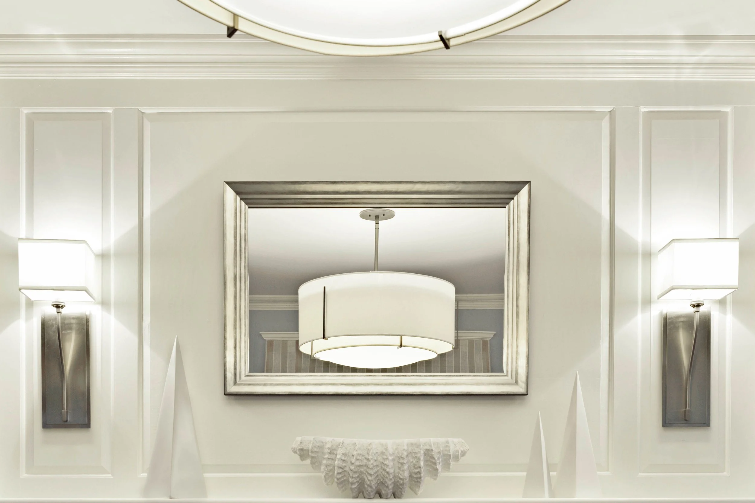 Fireplace mantle detail with refined trim, mirror, and chandelier in Indian Field residence in Greenwich, CT.
