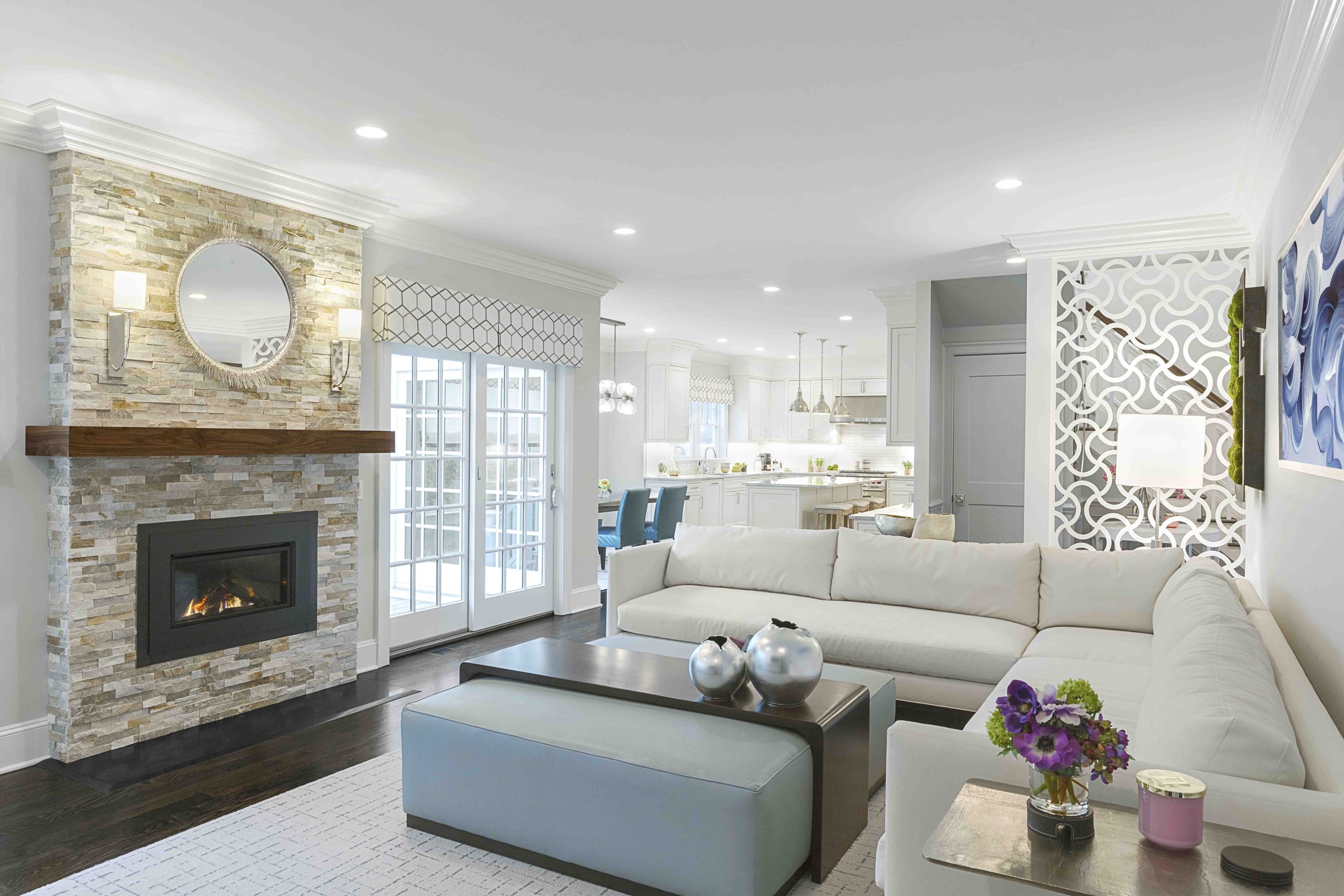 Wide view of the Glen Oaks family room in Rye, NY, designed by Luminosus Designs with a comfortable layout, layered lighting, built-in media center, fireplace surroudn, and custom furnishings.
