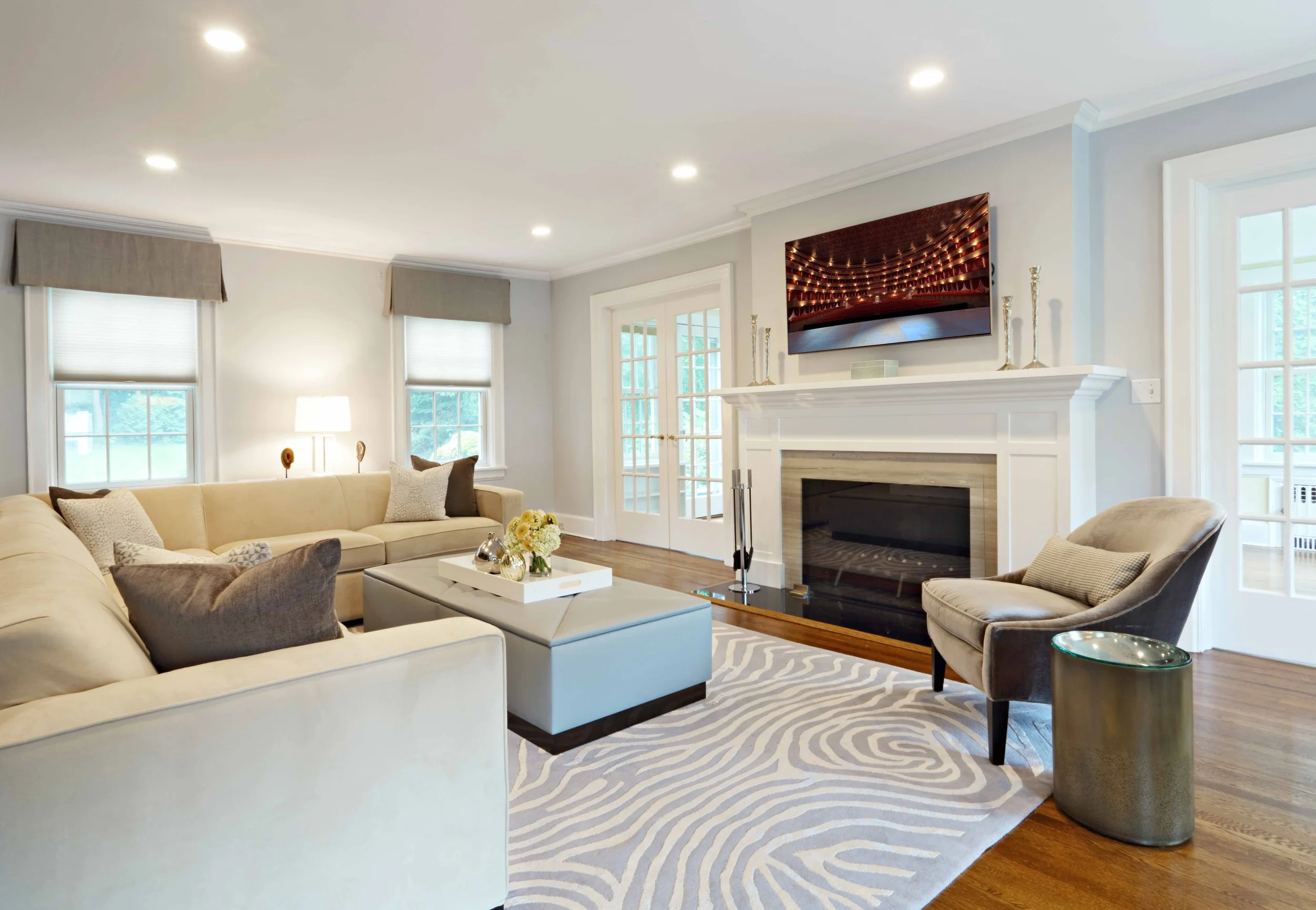 View of a sophisticated family room featuring a custom fireplace, upholstered seating, textured area rug, and curated accessories designed by Luminosus Designs in Scarsdale, NY.