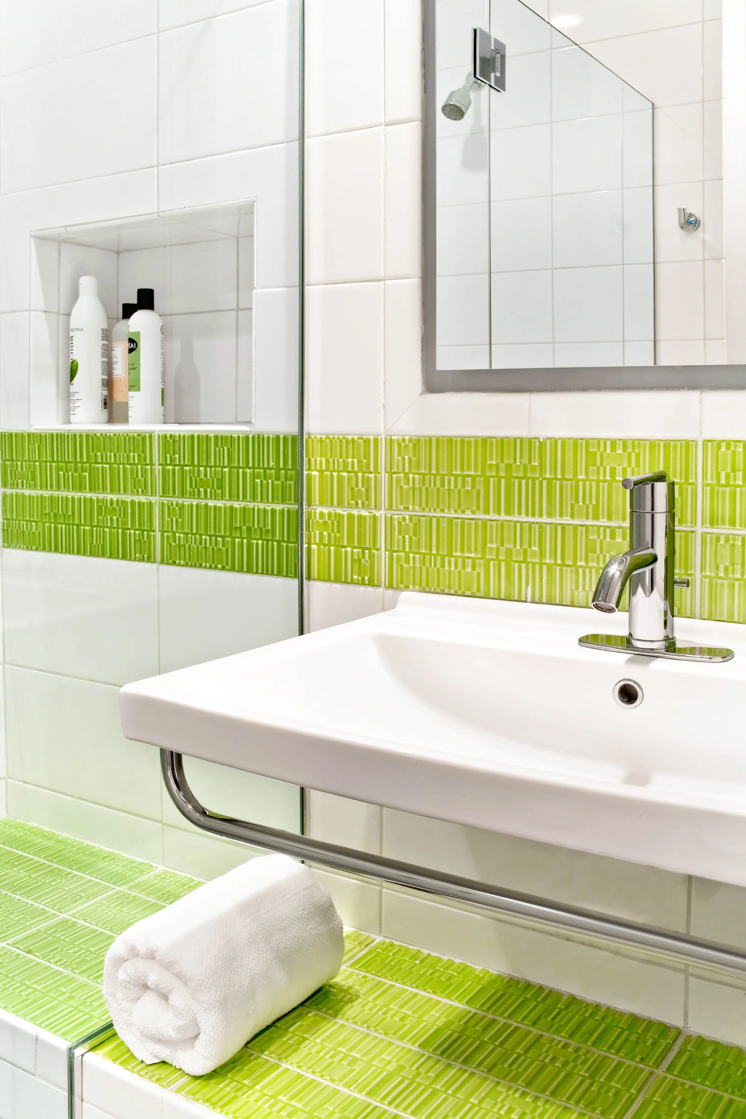 Close-up view of the Deerfield family bathroom in Pleasantville, NY featuring a floating vanity, custom shower bench, and fresh green tile accents, designed by Luminosus Designs.