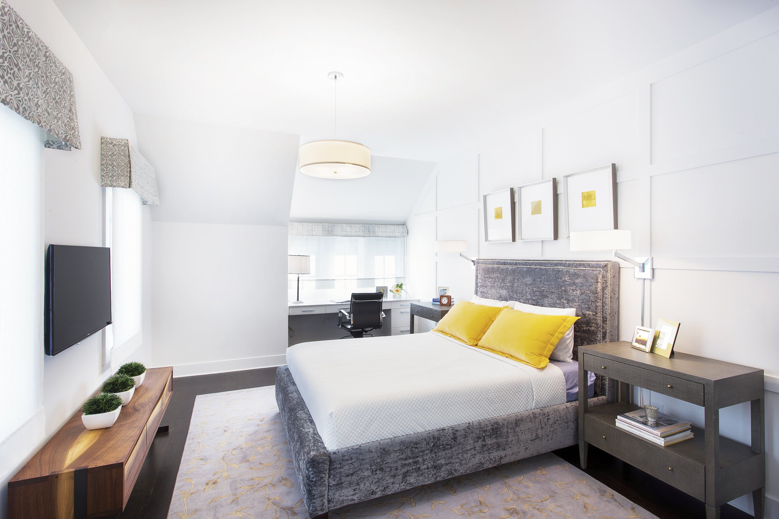 Wide view of a guest bedroom with layered neutral bedding, accent pillows, and a clean, tailored bedside setup.