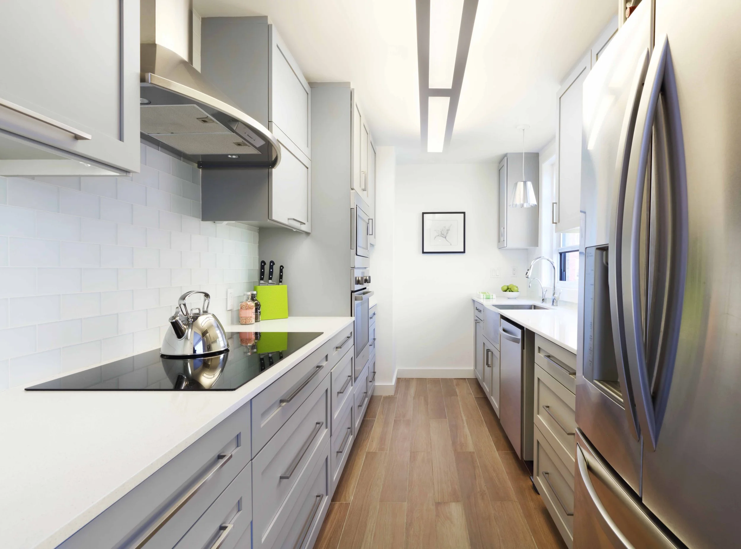 Modern apartment kitchen with sleek cabinetry, integrated appliances, and minimalist finishes in Doyer Apartment in White Plains, NY by Luminosus Designs.