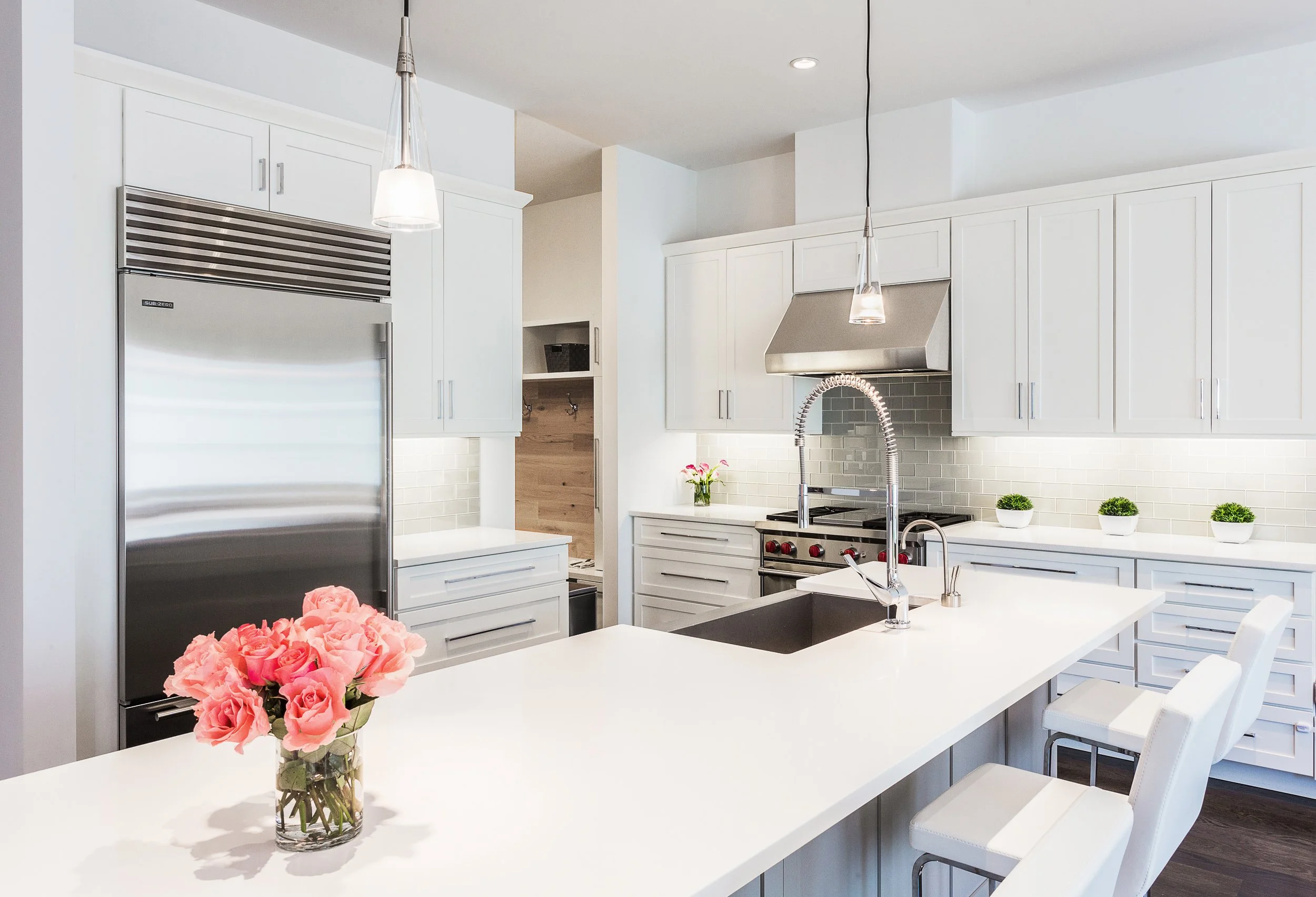 Close-up view of the kitchen island with undermount sink, chrome faucet, pendant lighting, and the range wall beyond in Kensett House in Darien, CT.