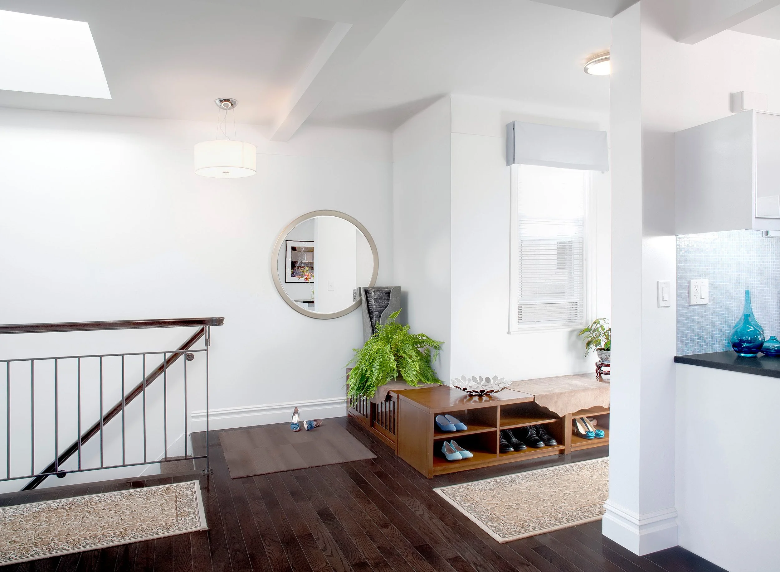 Close-up of staircase at the Muliner House in Bronx, NY featureing a wrap-around bench with shoe storage below.