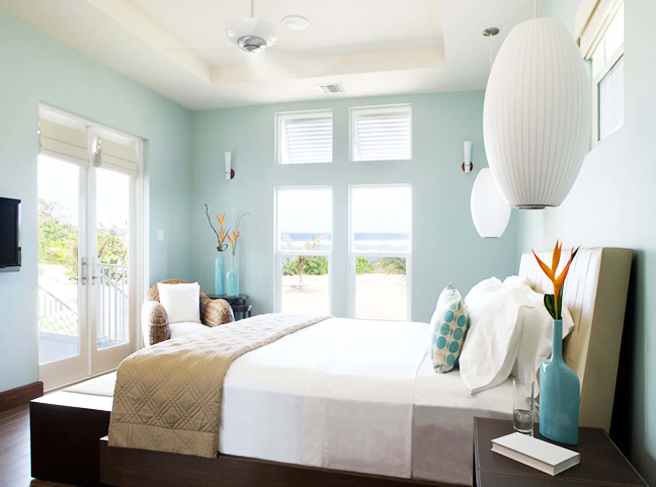 Coastal bedroom design in Grand Cayman guest villa with soft blue walls and ocean views.