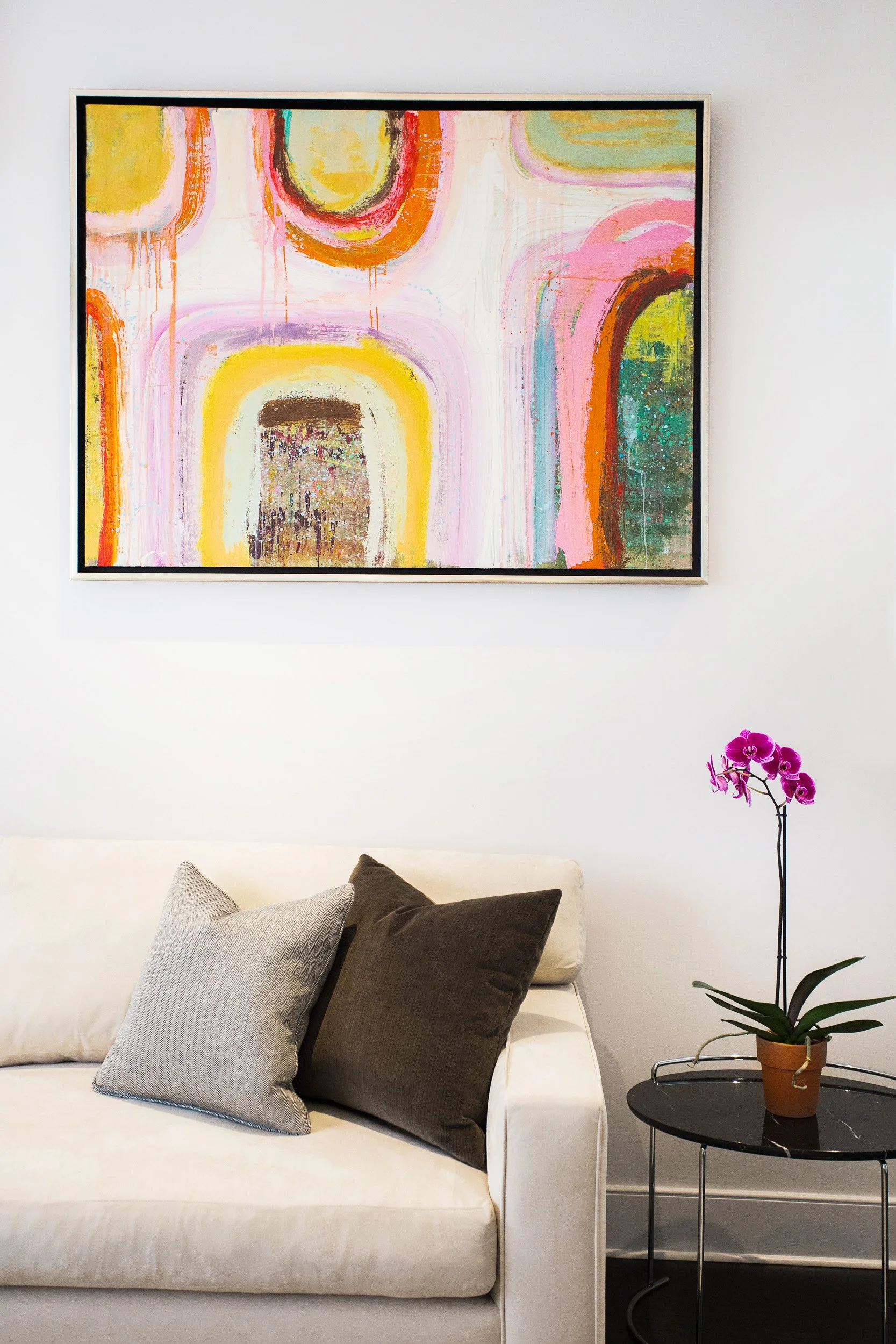 Detail shot of a styled sofa wall with abstract artwork and an orchid arrangement.