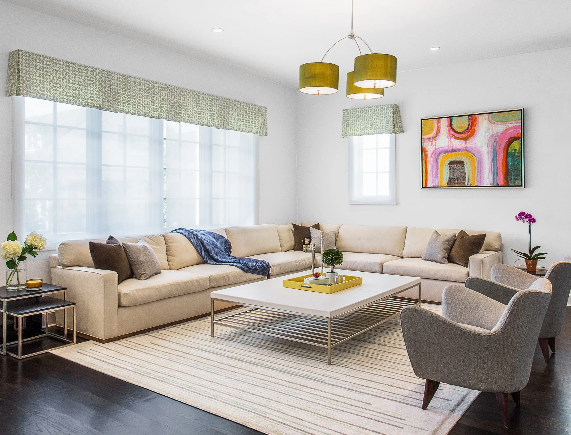 Wide view of the family room seating arrangement with a modern sectional, custom rug, and bold abstract artwork.