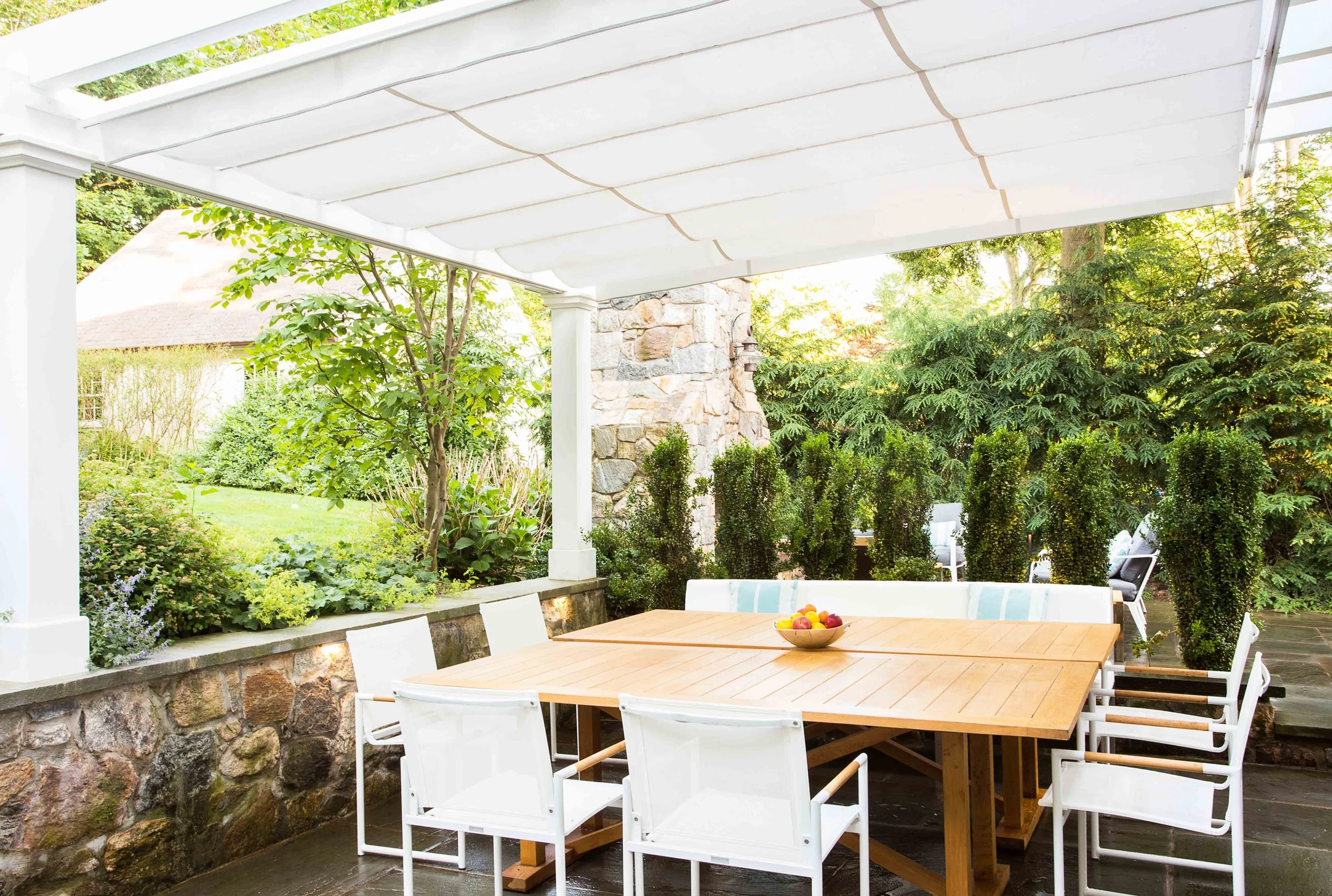 Wide view of outdoor dining area with pergola shade closed at the Indian Field Outdoor project in Greenwich, CT.