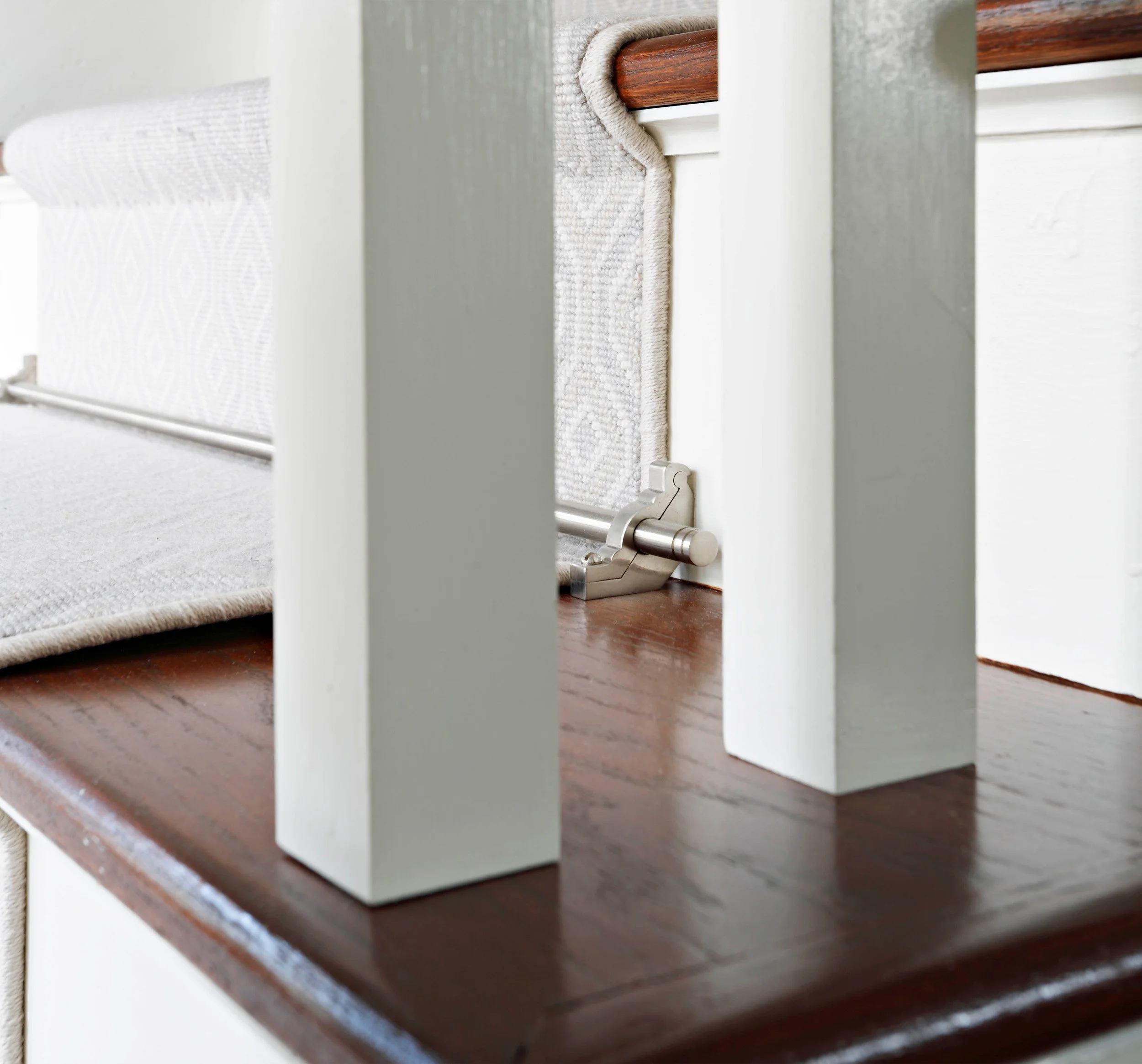 Detail of staircase runner secured with custom stair rod hardware in Indian Field residence in Greenwich, CT.