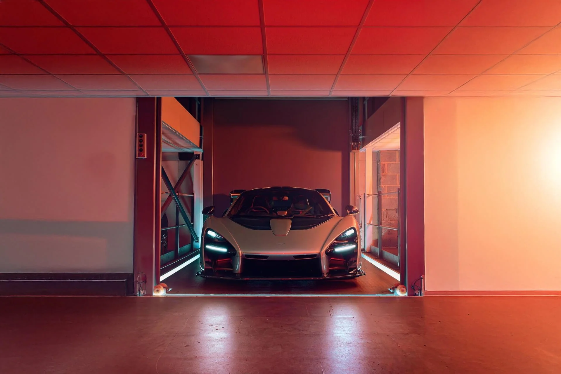 A white sports car parked inside an industrial-style garage with warm lighting.