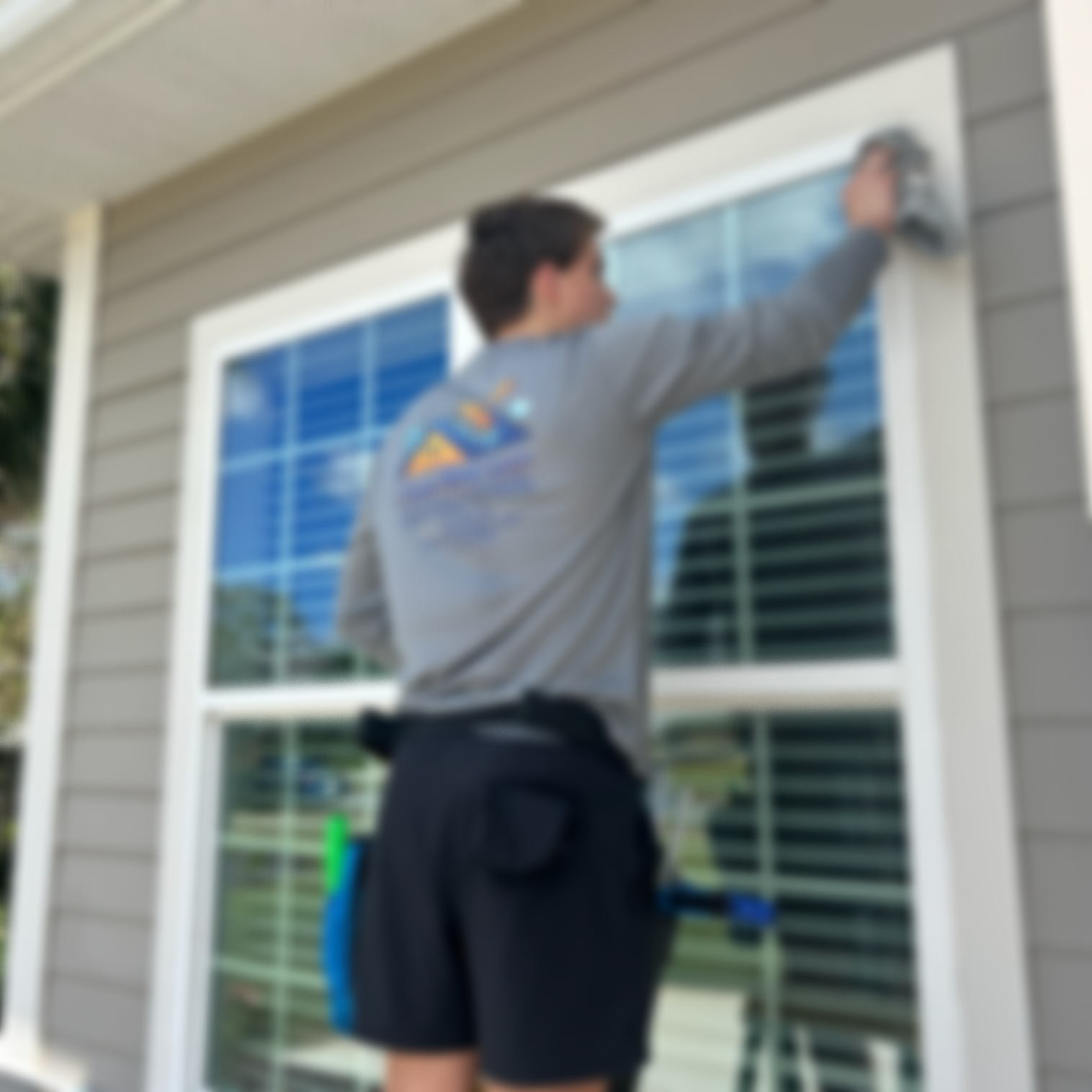 A person cleaning a large window on the exterior of a house.