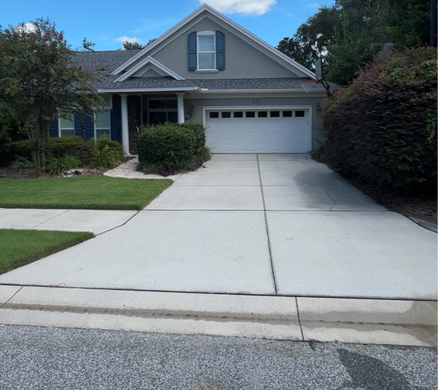 Front view of a suburban house with a driveway, manicured lawn, and trees.
