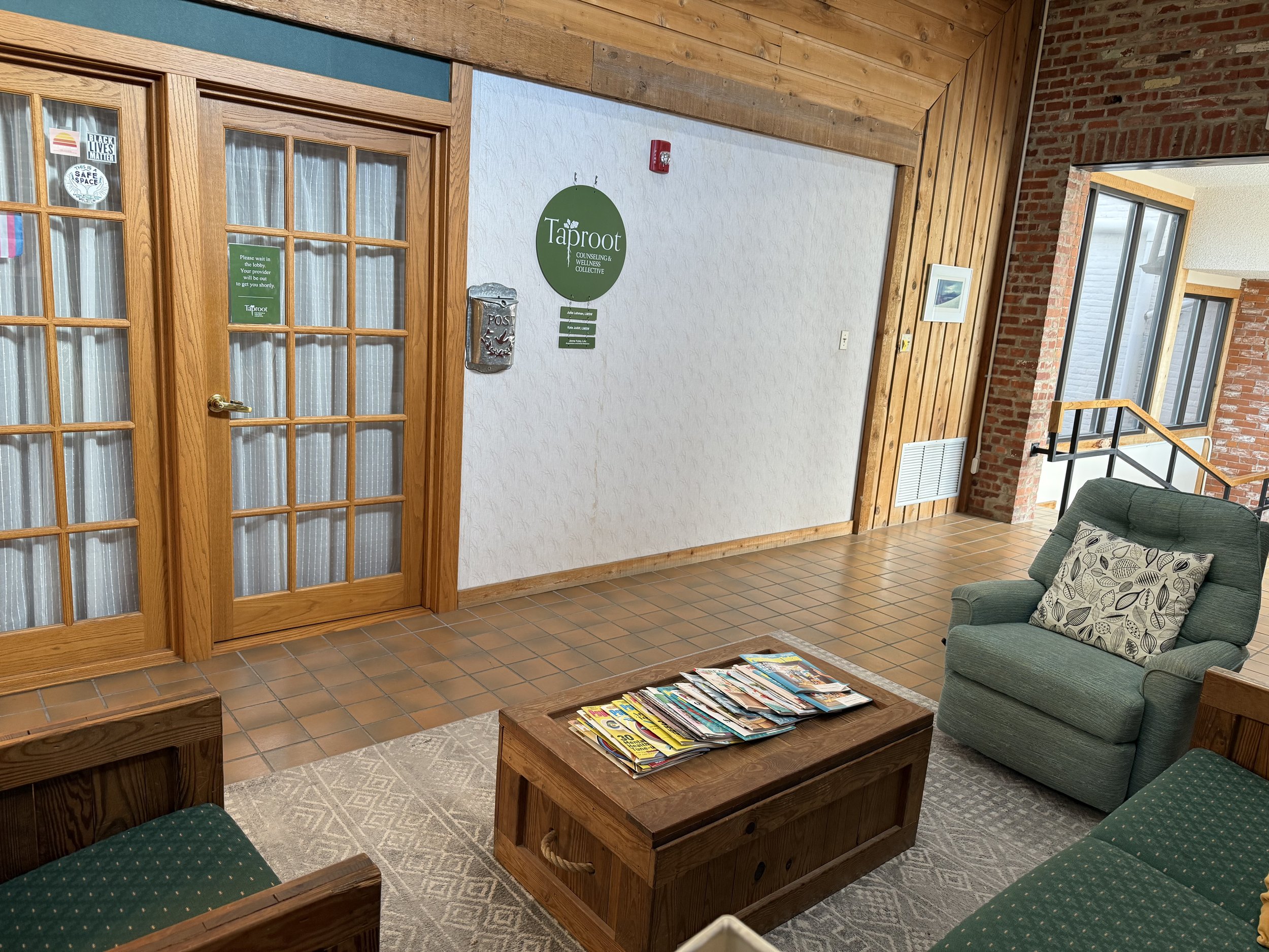 Entrance to the shared wellness suite at Old Mill Plaza in Newton, KS, featuring the Taproot Counseling & Wellness Collective sign with practitioner names. This is the main entryway for Taproot Acupuncture & Herbal Medicine patients.