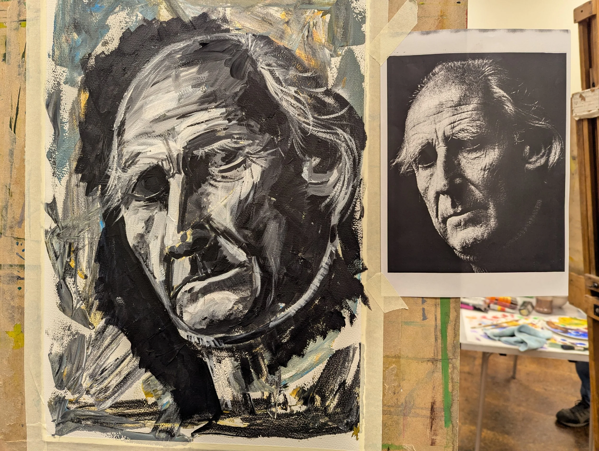 A black and white painting of a man, with a photograph of the same man with similar features, including wild hair, displayed next to it.