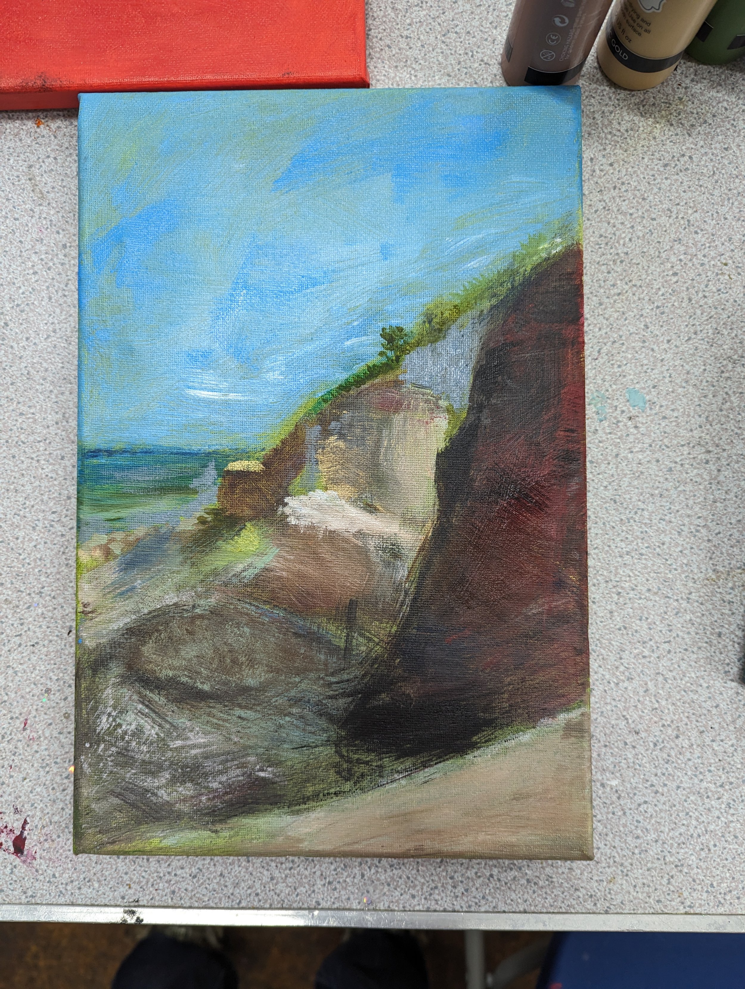 A landscape painting of a rocky shoreline with a blue sky, some green vegetation, and rock formations near the water.