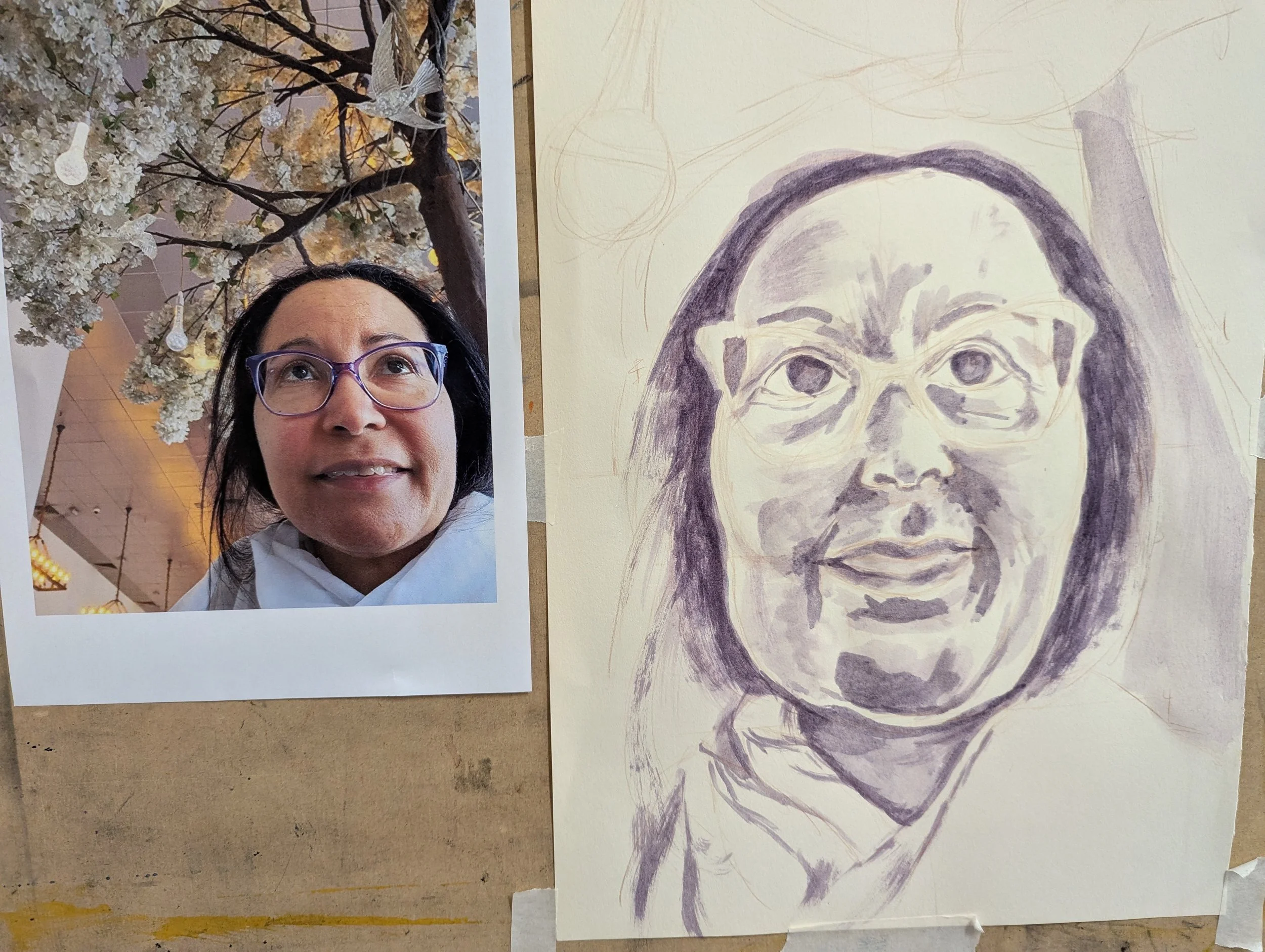 A photo of a woman with black hair, wearing glasses, and a white shirt, looking up, with a background of tree blossoms. Next to the photo is a sketch of the same woman, capturing her facial features.