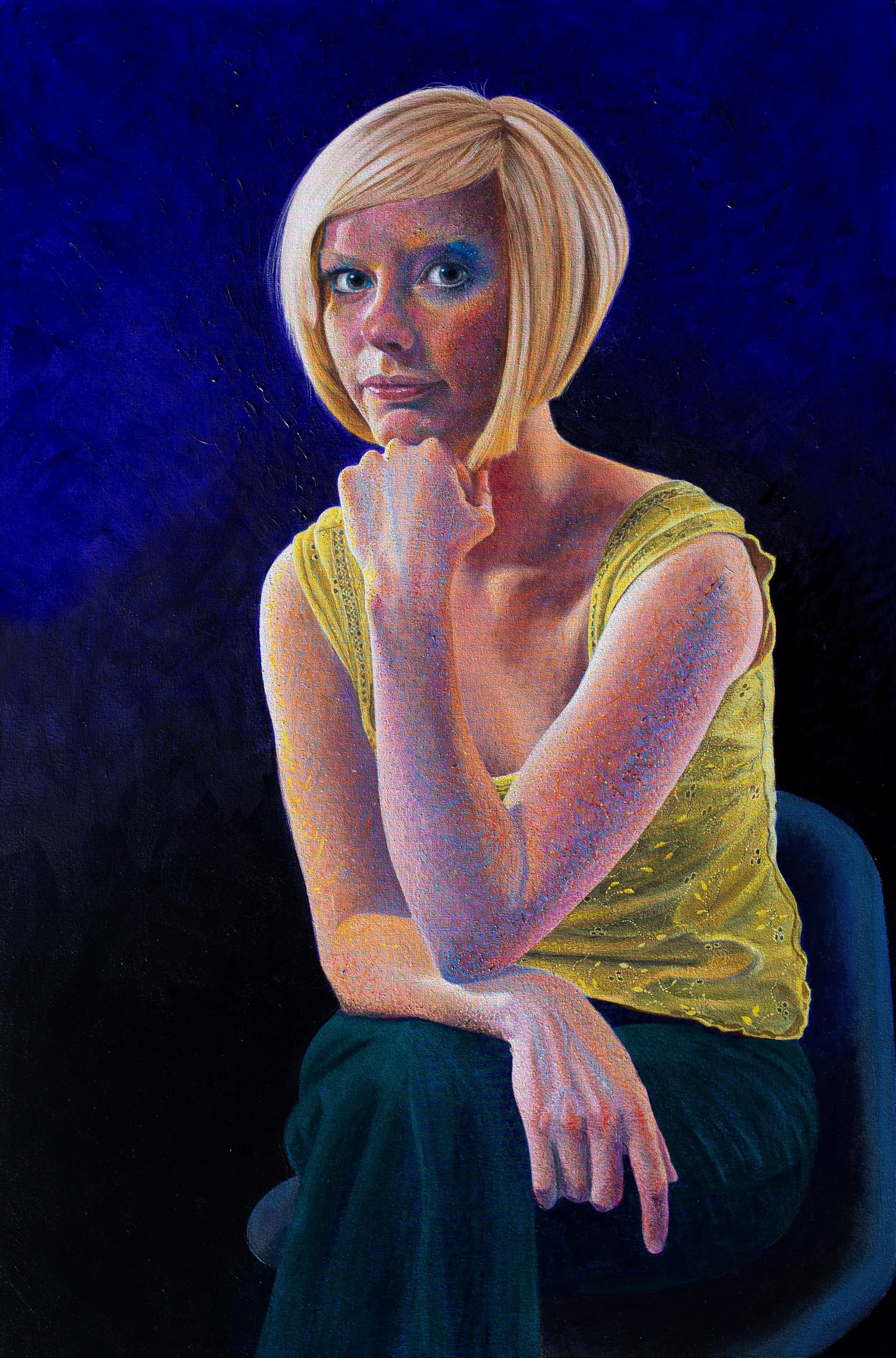 Portrait of a Hazel wearing a yellow top, sitting pensively, engaging the viewer, against a deep violet background.