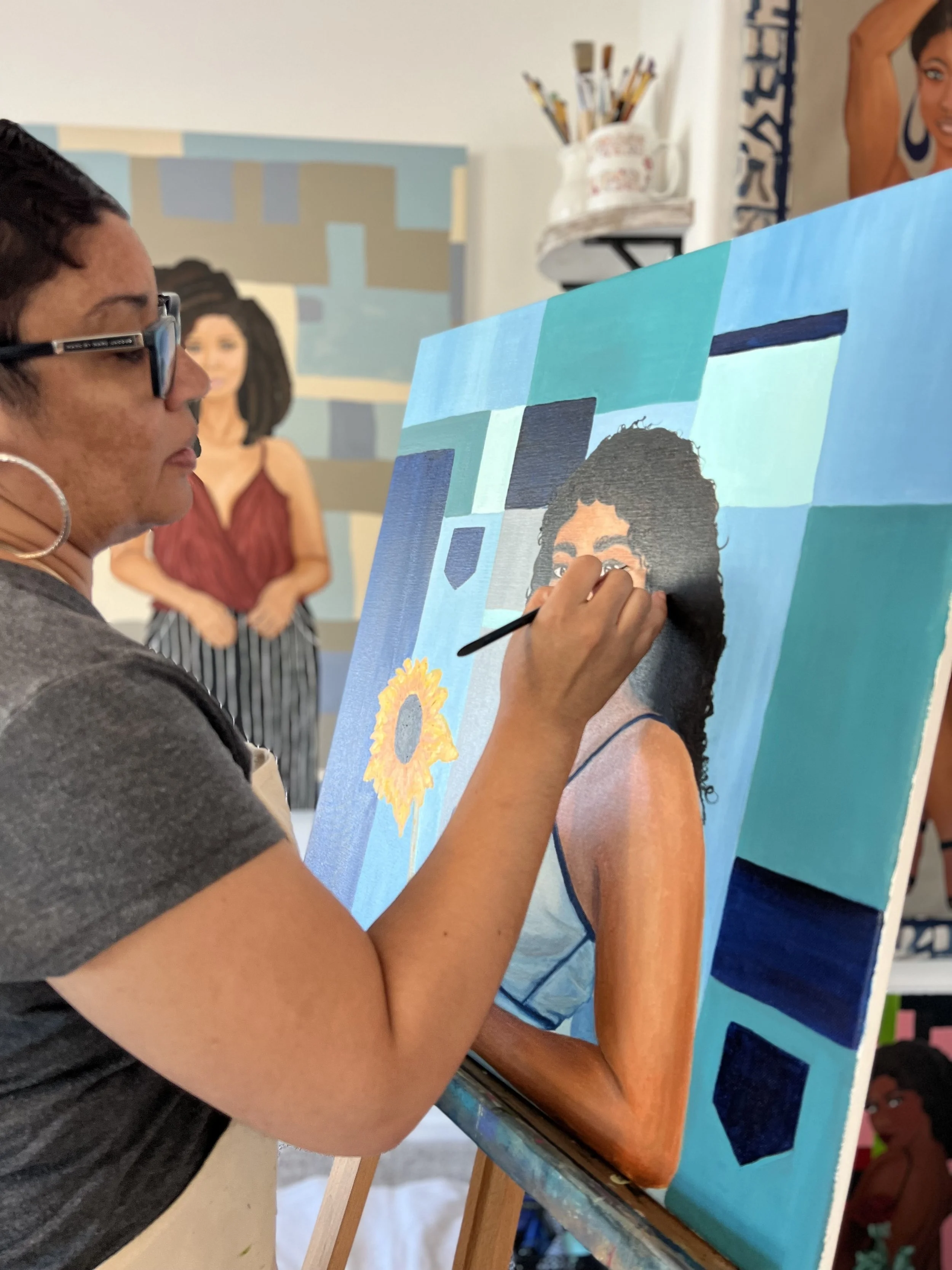 An artist is painting a portrait on a large canvas in a studio, with a focus on a woman with curly hair. Other artwork is visible in the background.