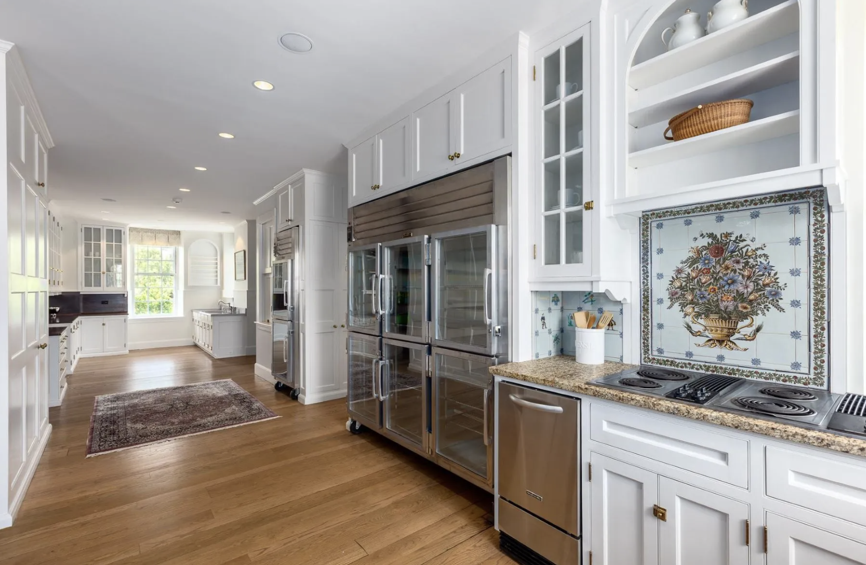 Bright kitchen with white cabinetry, stainless steel appliances, wood flooring, and decorative tile backsplash