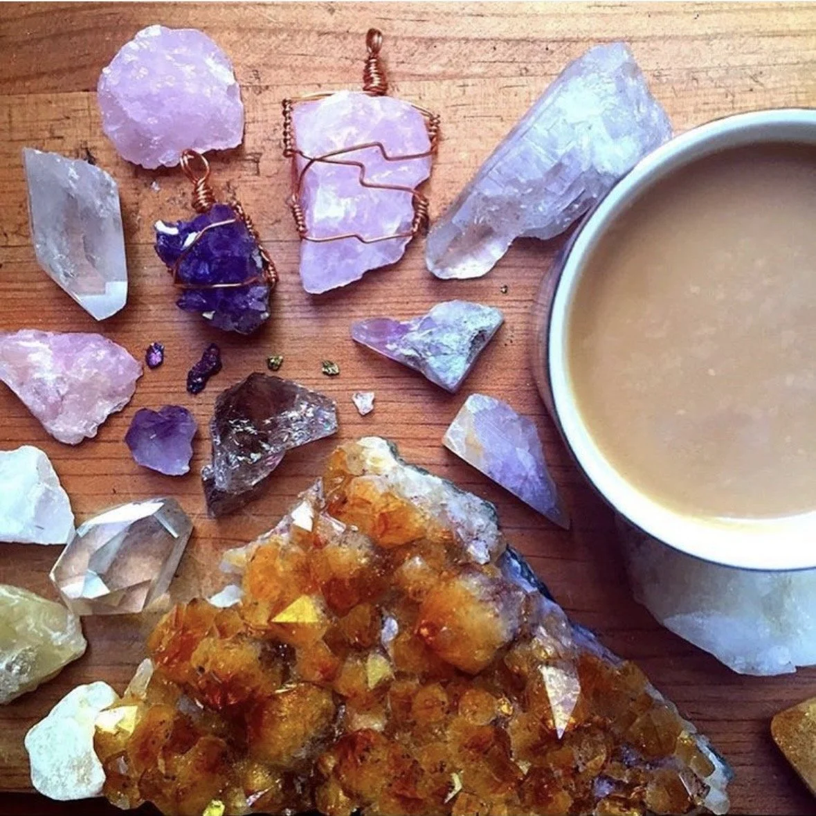 A cup of coffee sits among crystals and handmade crystal jewelry.