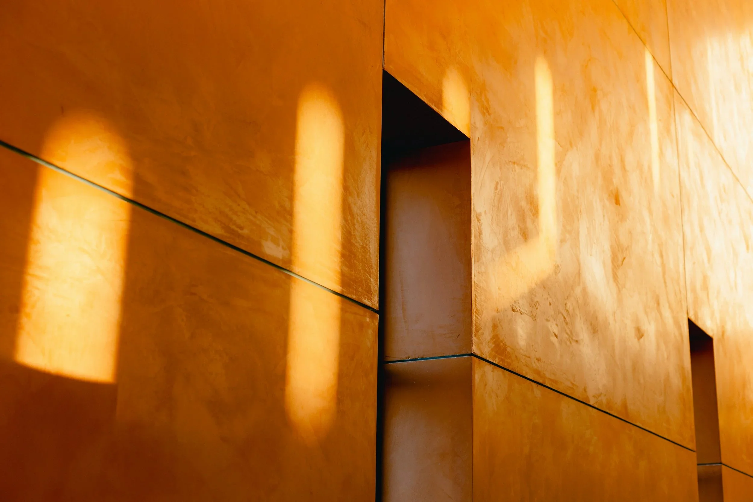 Close-up of a wooden surface with a warm orange-brown stain, showing the grain and panel edges.