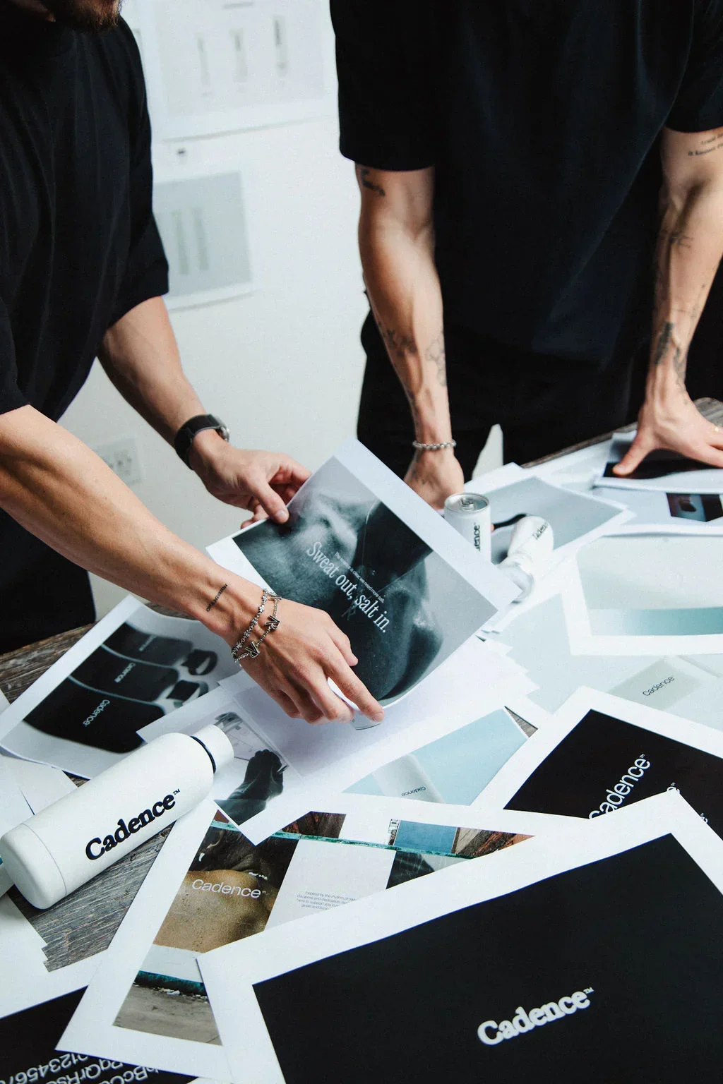 People working on a project with printed materials and a water bottle on a table.