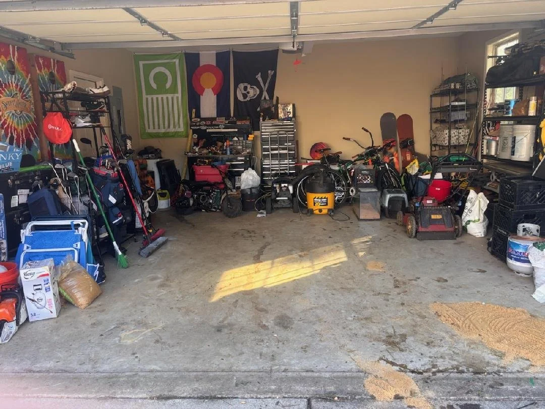A clean garage with organized storage shelves and bins, some tools, and an open garage door letting in natural light.